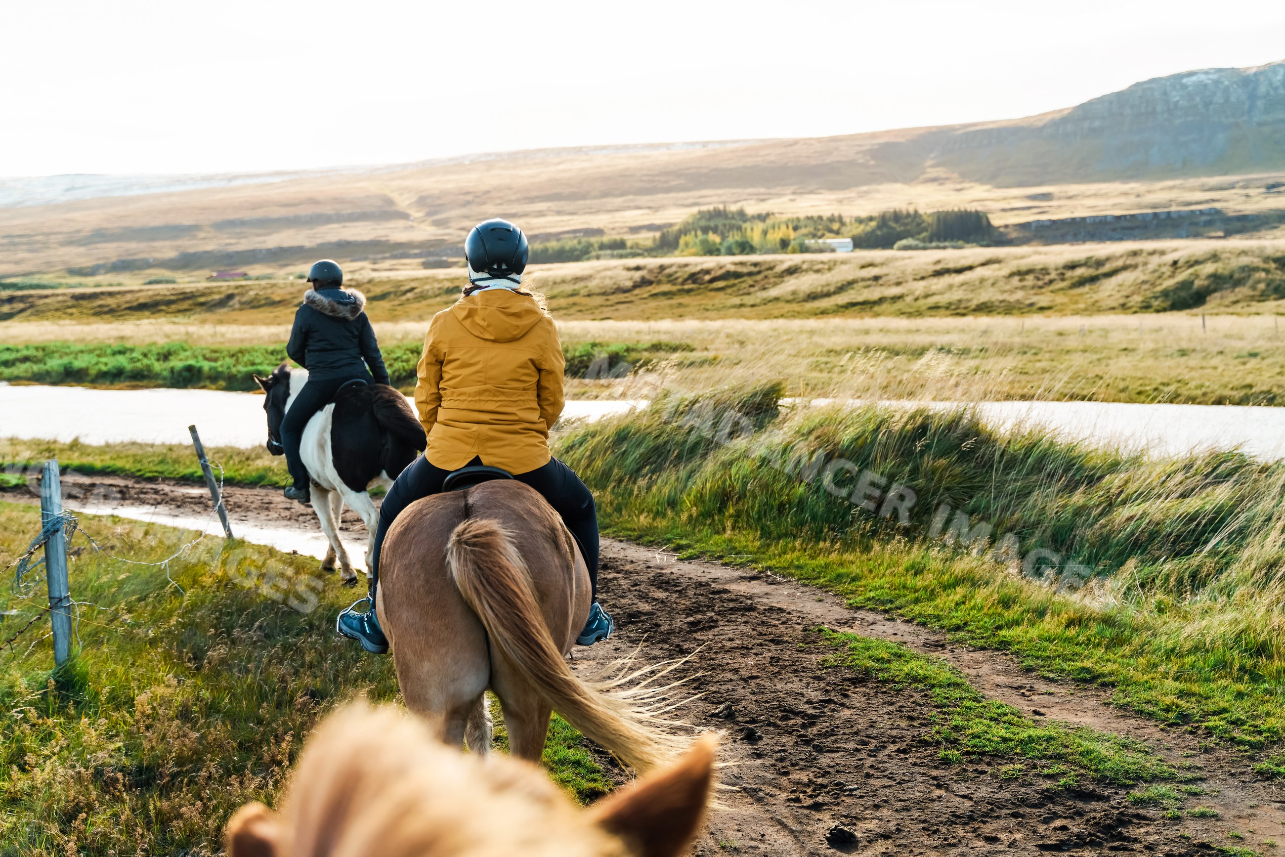 Two riders enjoying horseback trail riding along a river