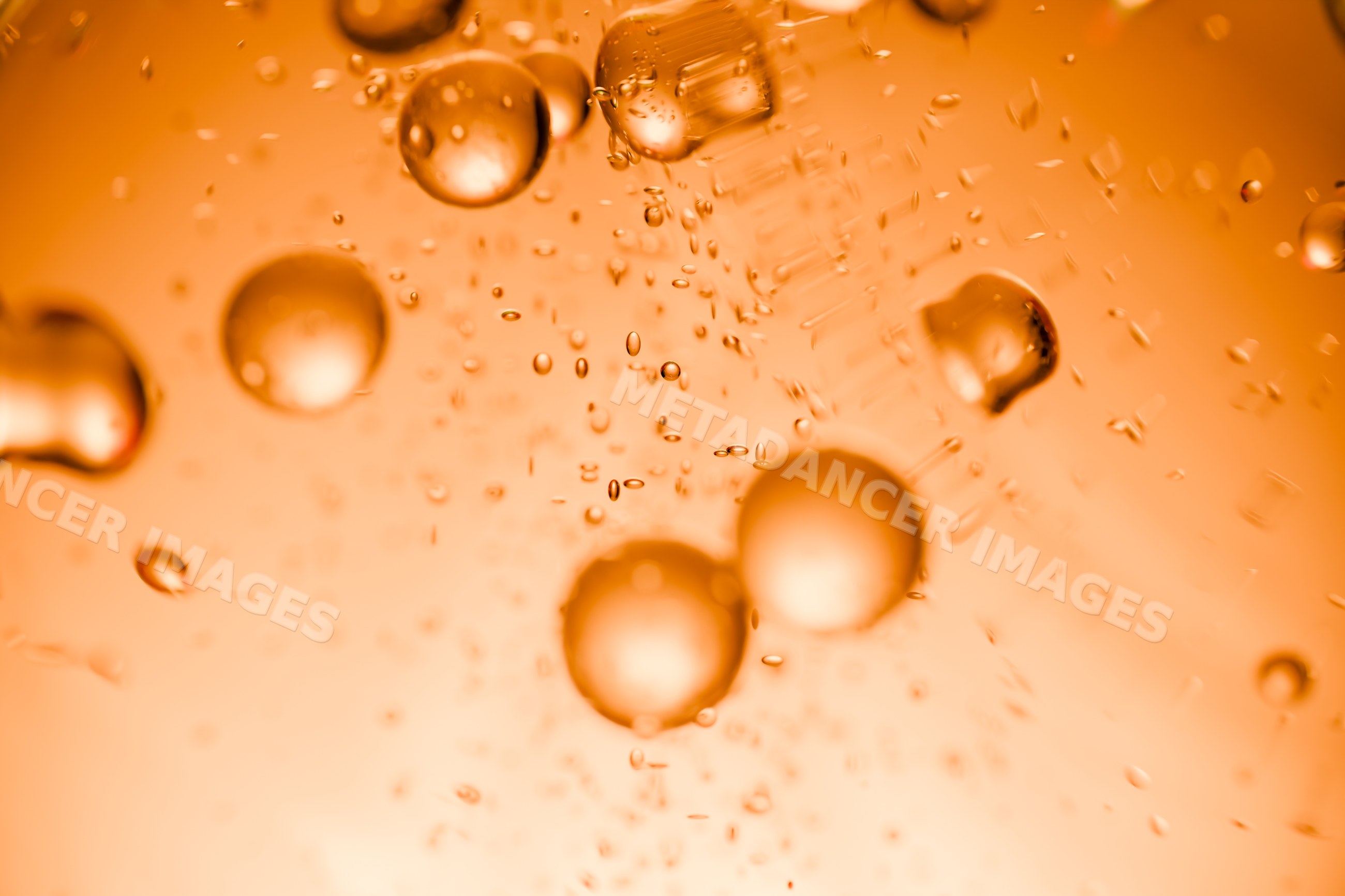 Orange liquid bubbles suspended in bright abstract macro background