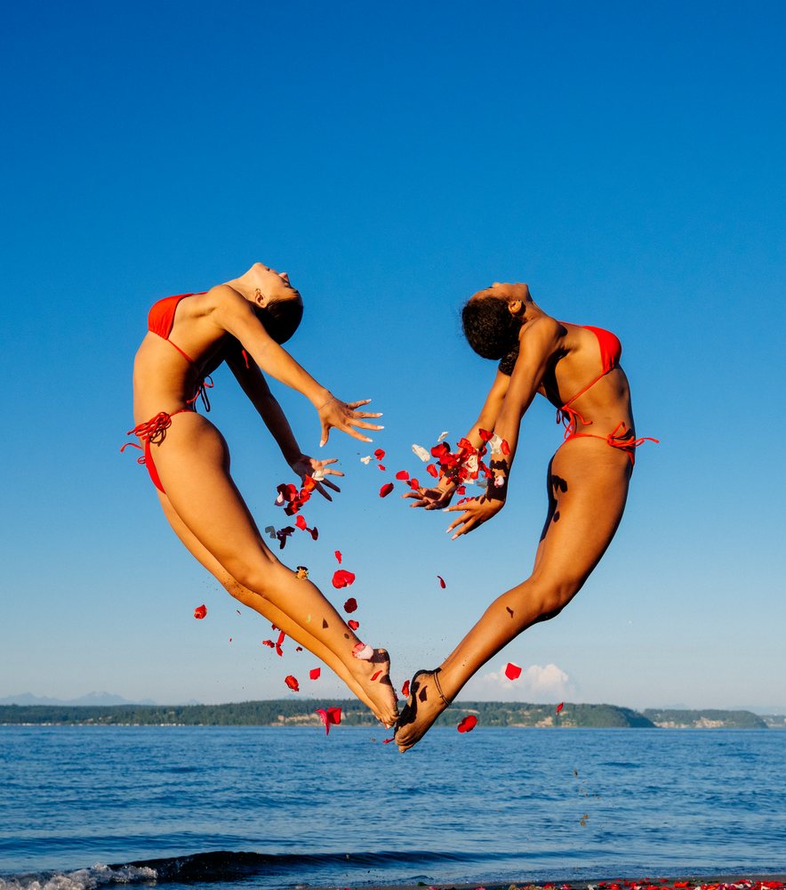 Two women performing partner acrobatic yoga on a beach in WA, USA