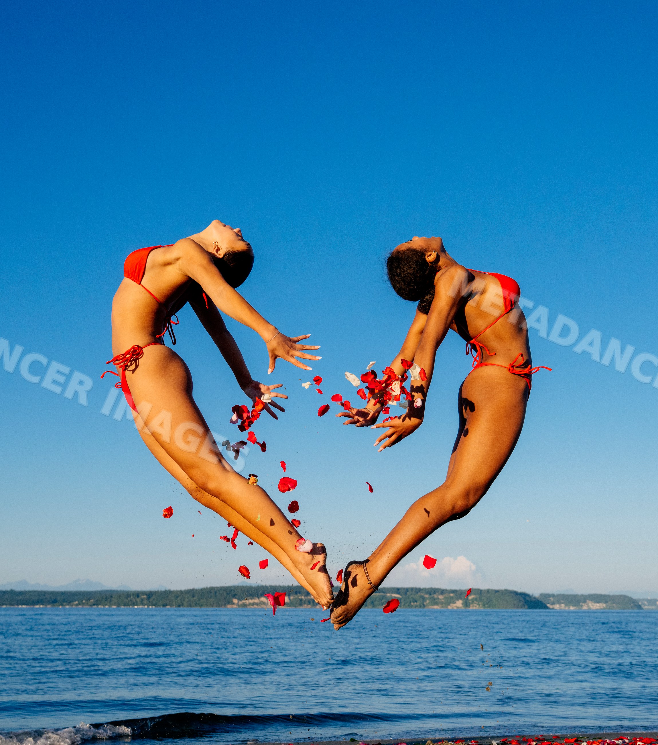 Two women performing partner acrobatic yoga on a beach in WA, USA