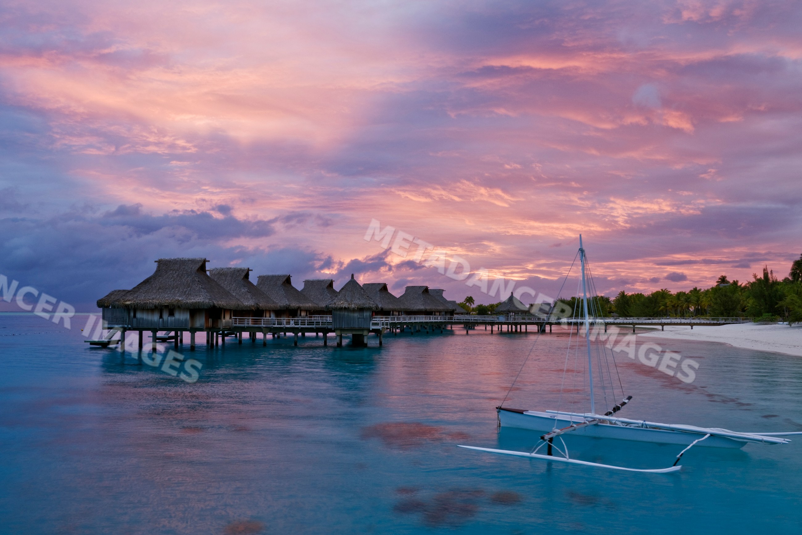 Overwater bungalows and sailboat at sunset, french polynesia