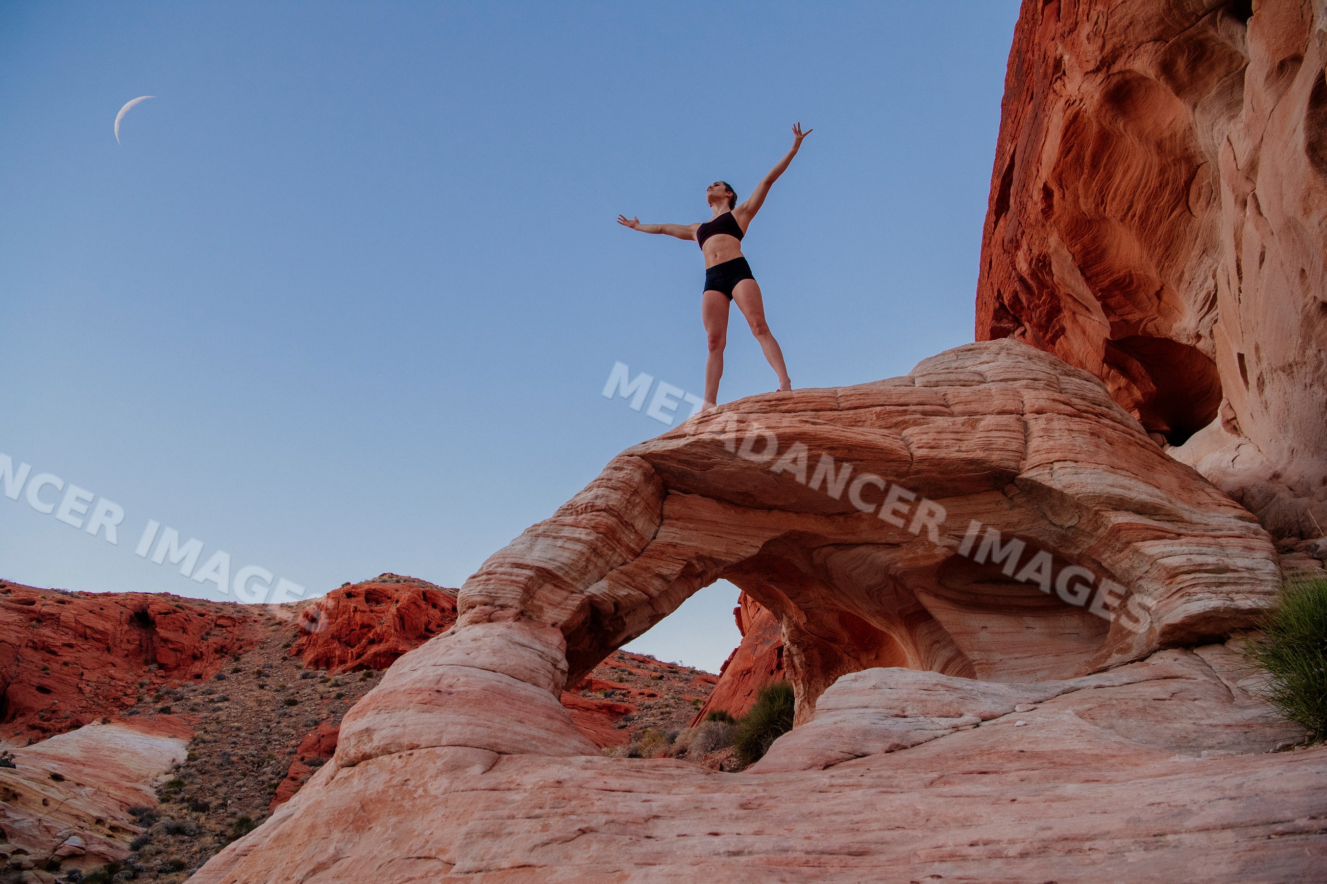 White woman practicing yoga pose on red rock formation