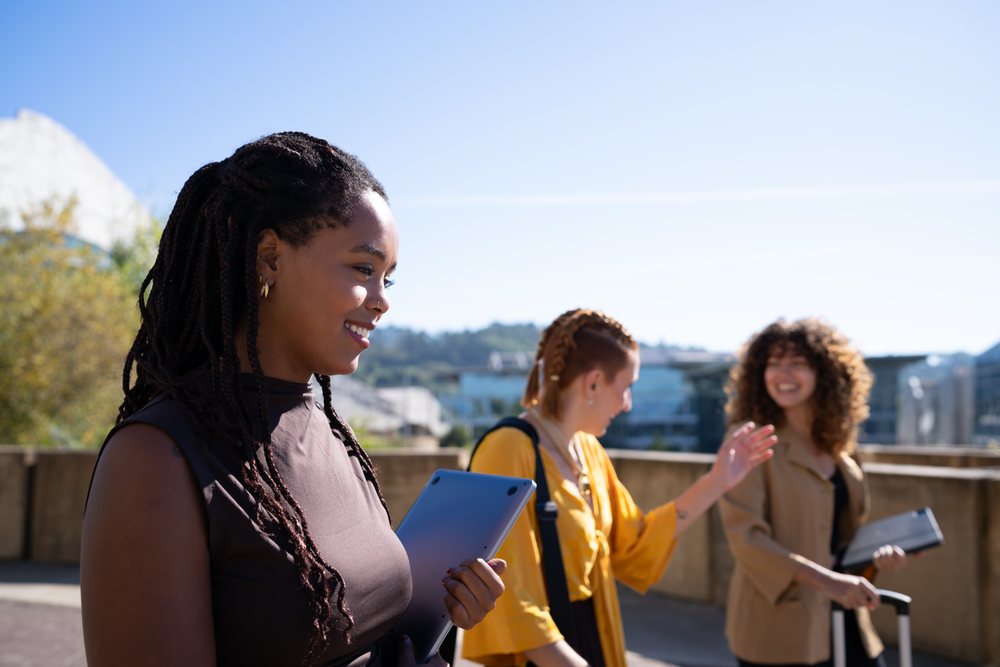 Three African American and white women walking and chatting outdoors