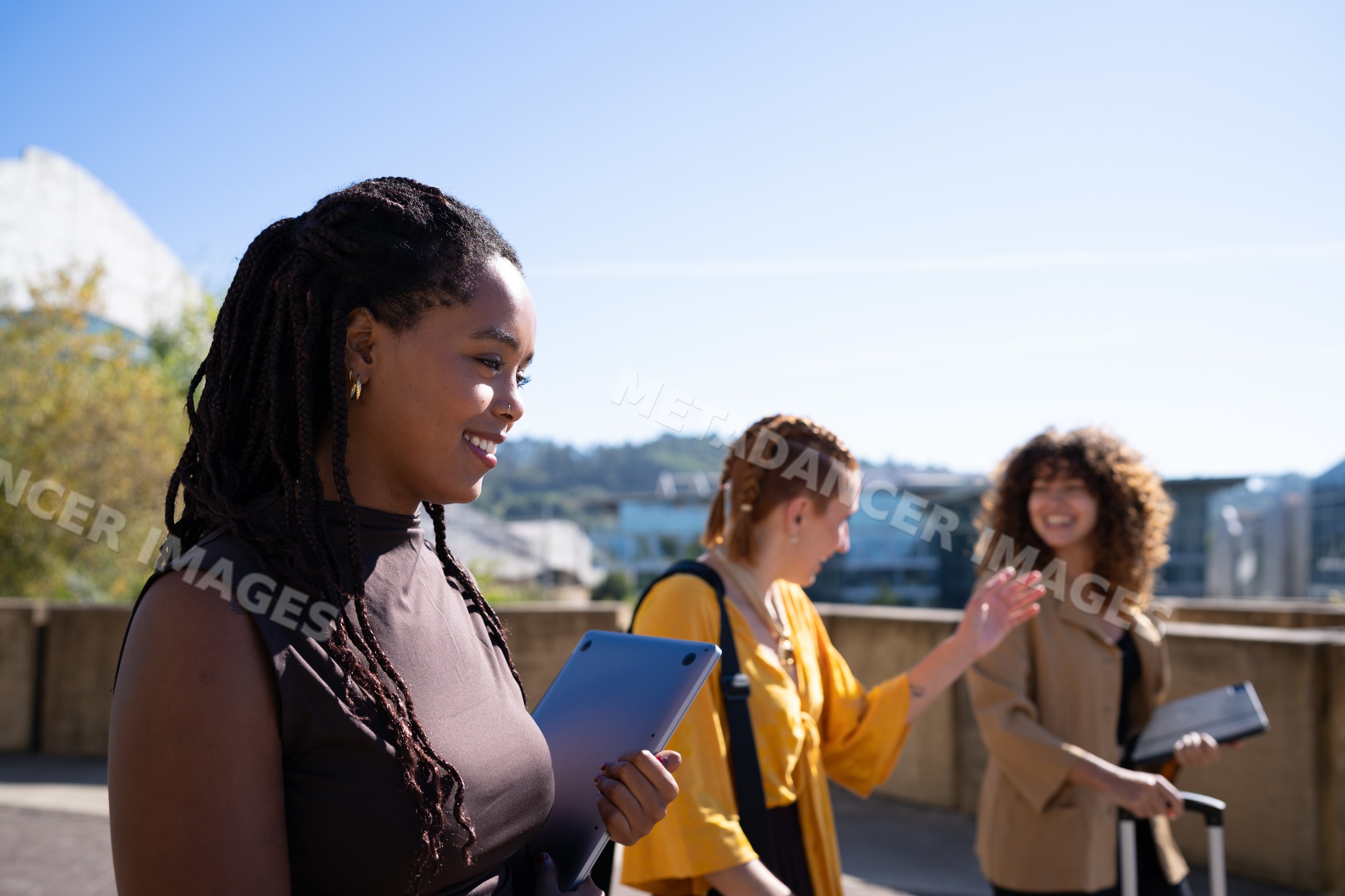 Three African American and white women walking and chatting outdoors