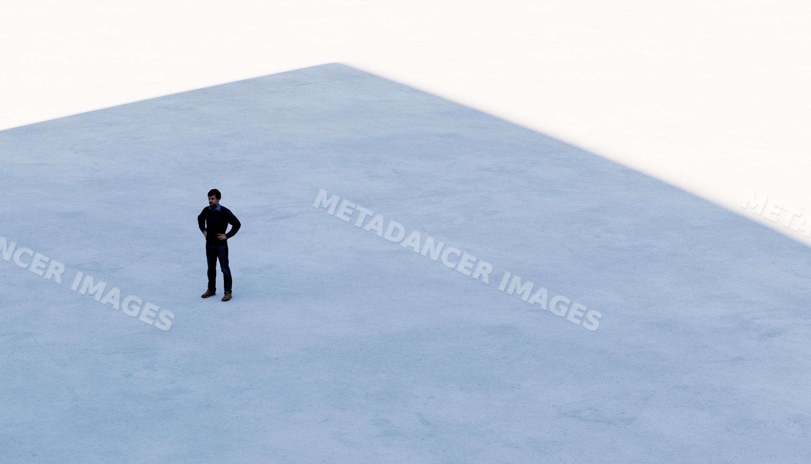 A man standing alone on a large concrete floor with shadow