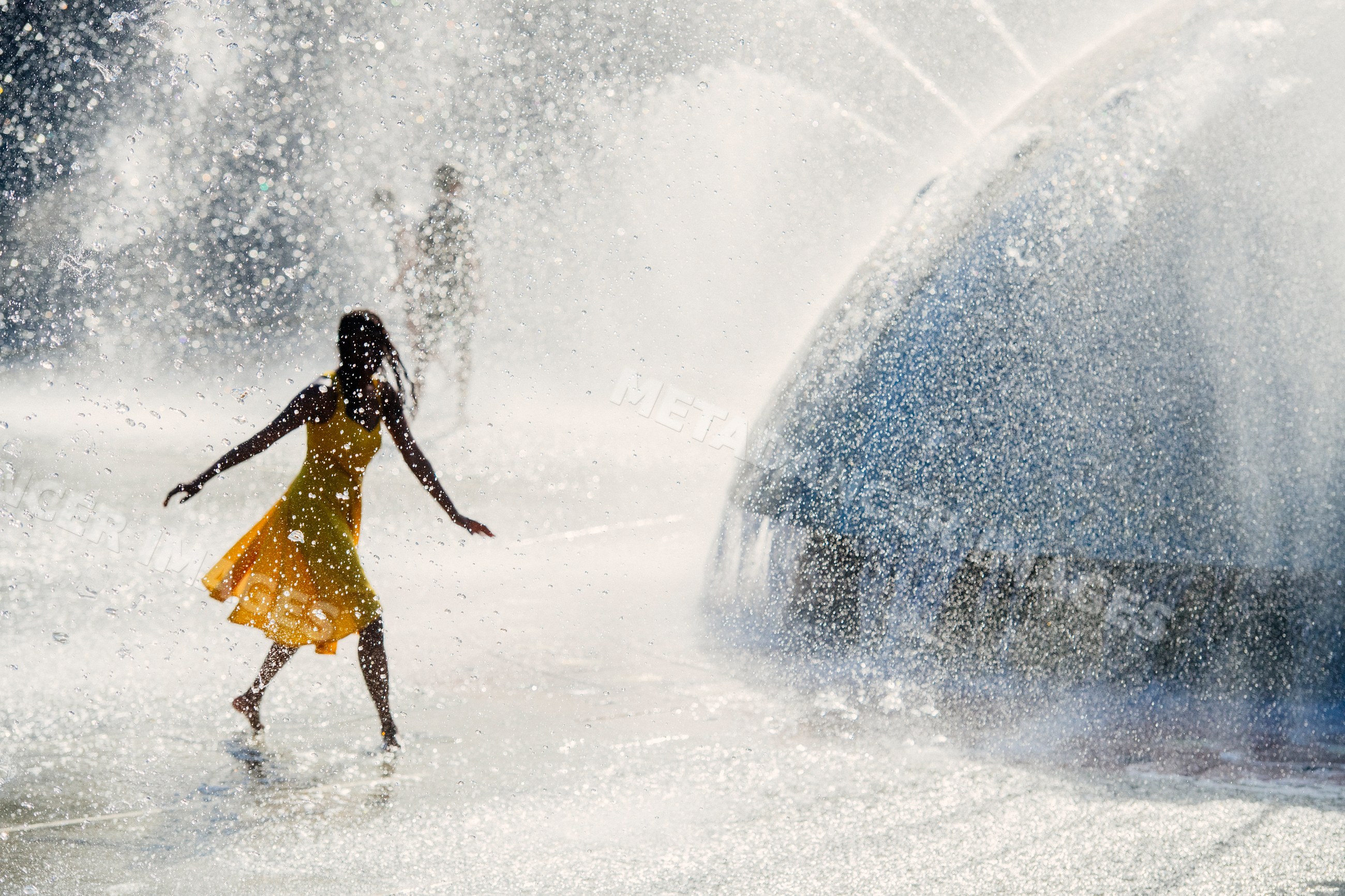 South Asian woman enjoying water fountain splash in a public park