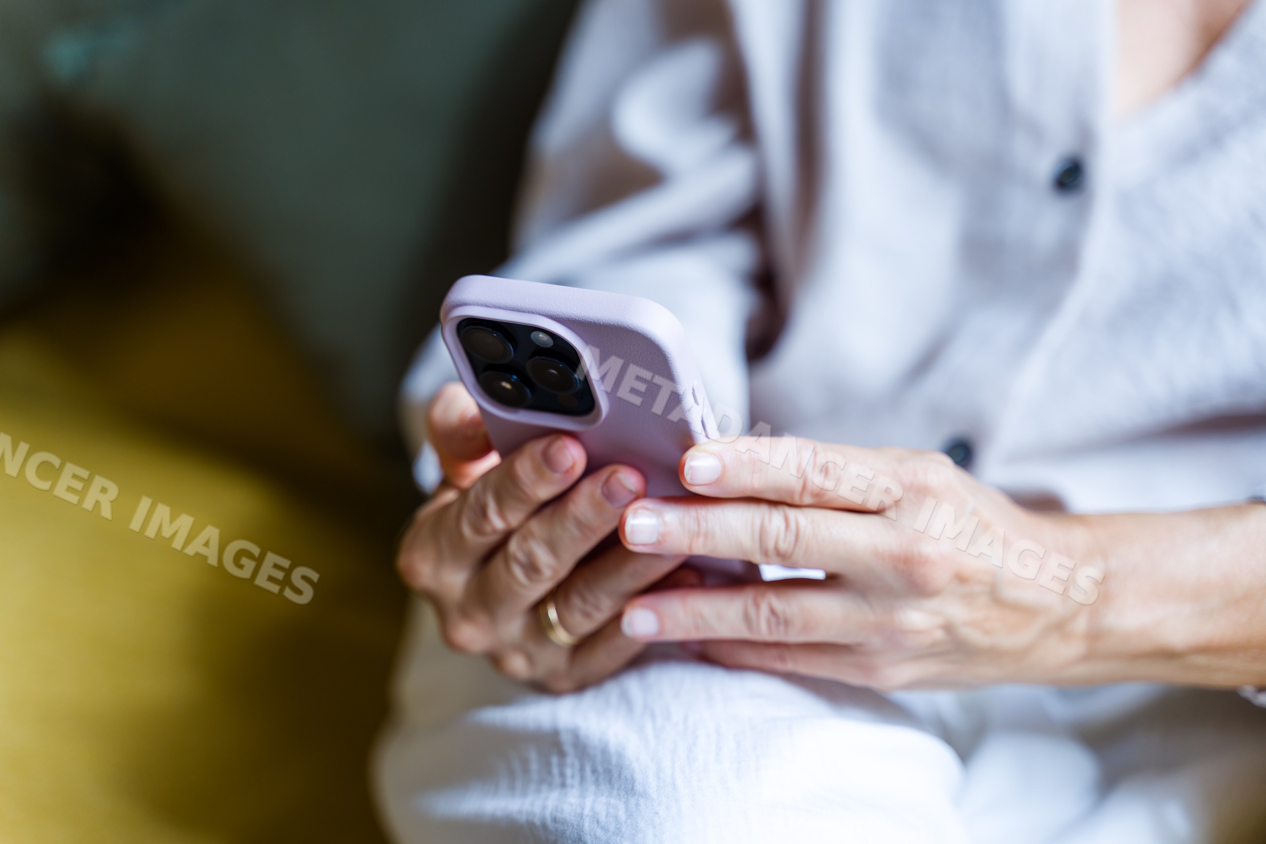White adult hands holding and using a smartphone indoors