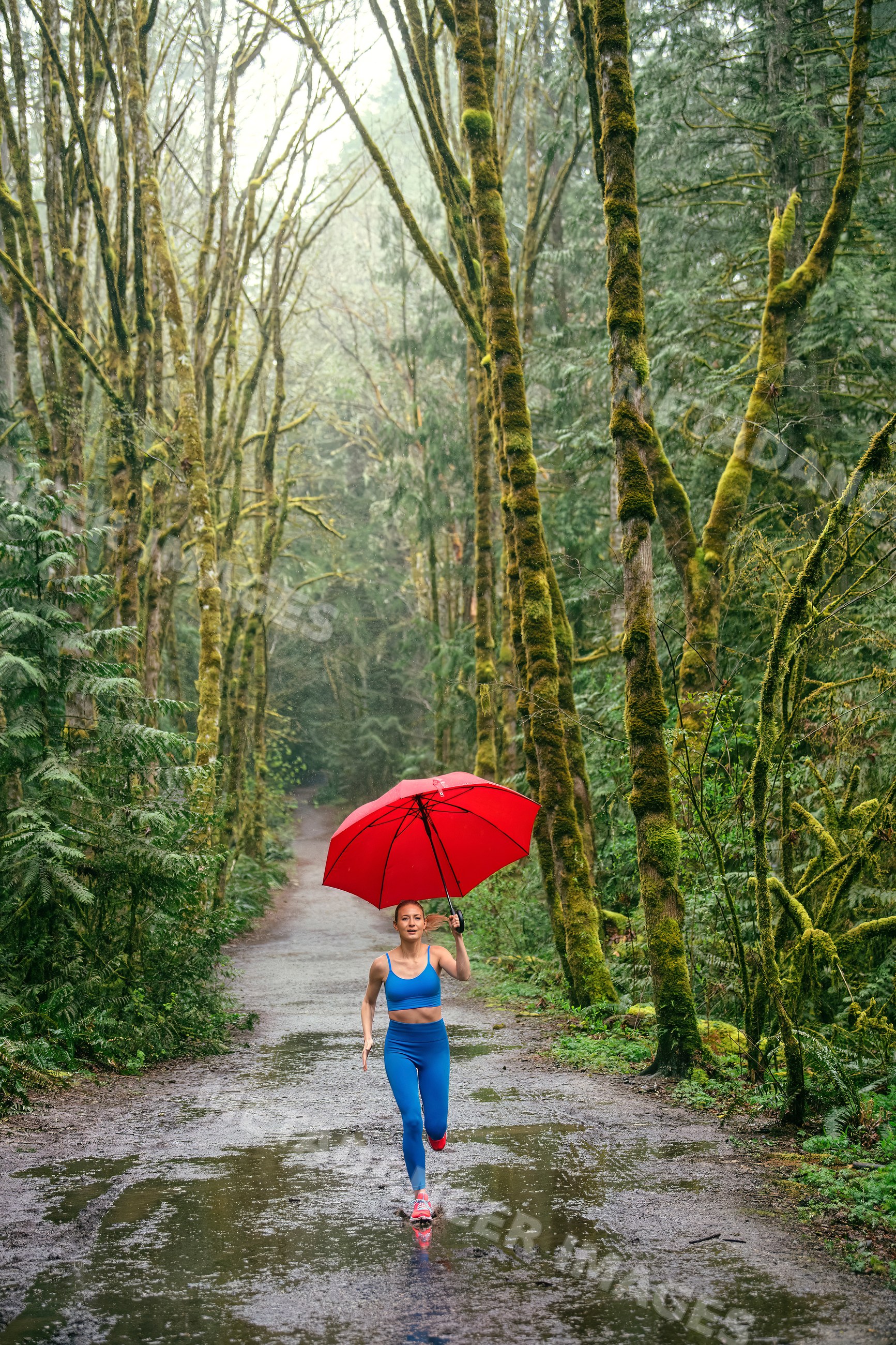 White woman running on forest trail with red umbrella in rain