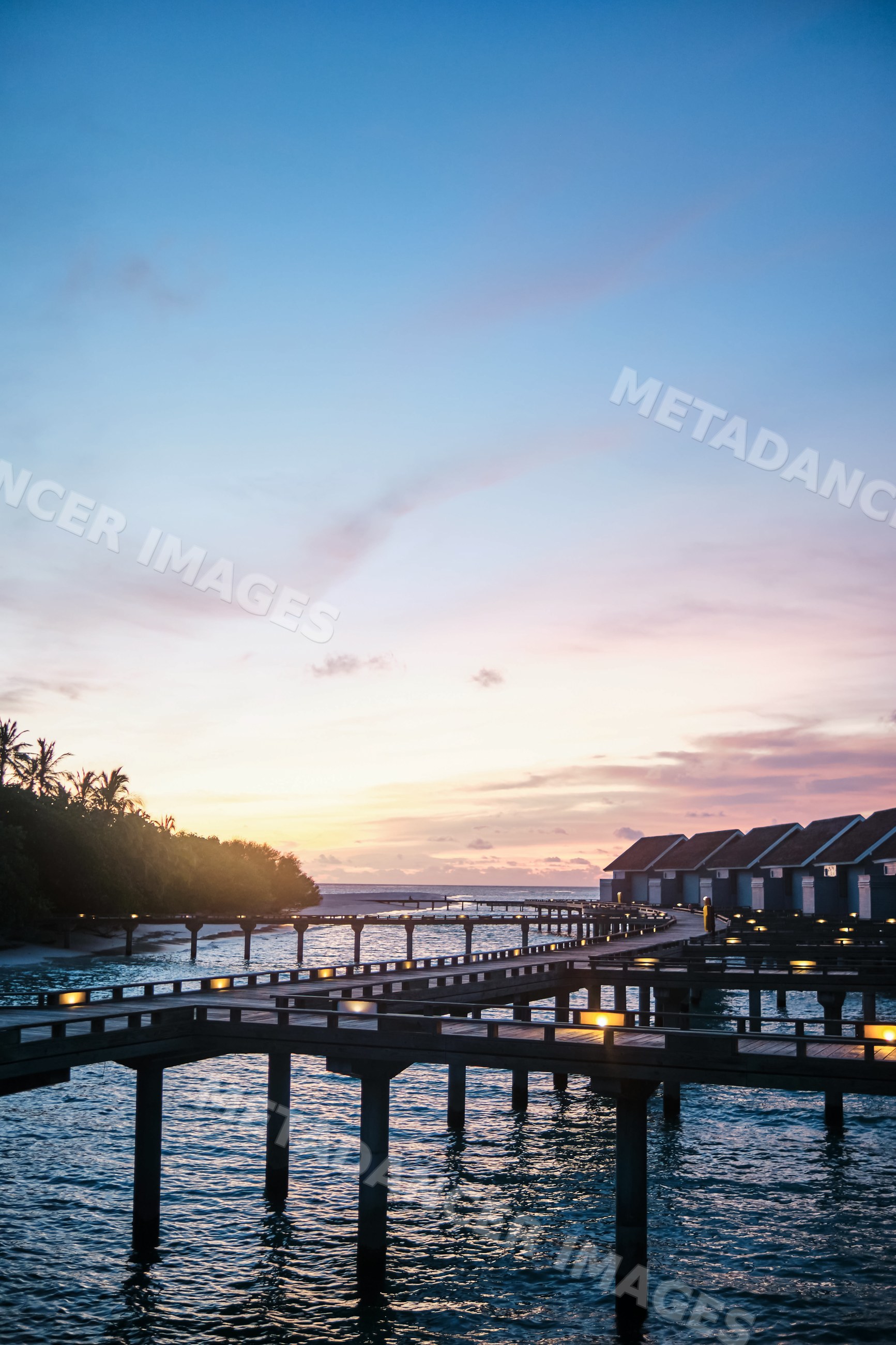 Wooden walkways linking overwater bungalows at sunset in the Maldives
