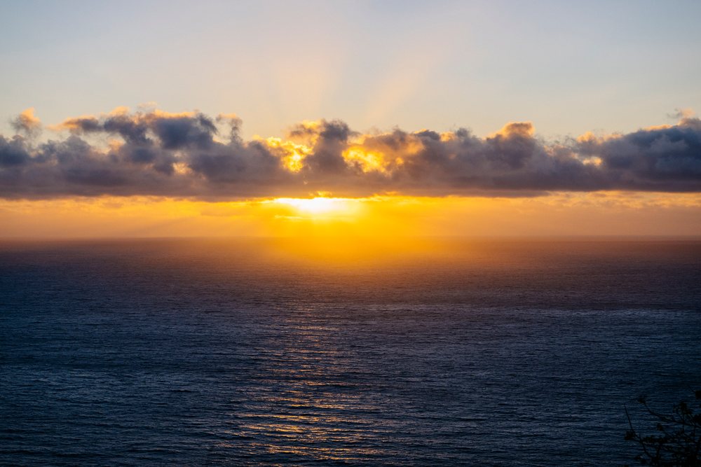 Sunset over ocean with clouds and golden sunlight