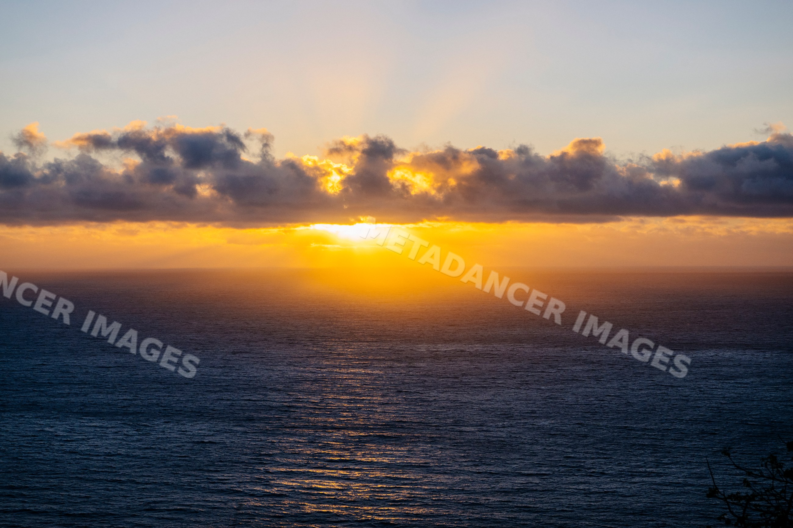 Sunset over ocean with clouds and golden sunlight