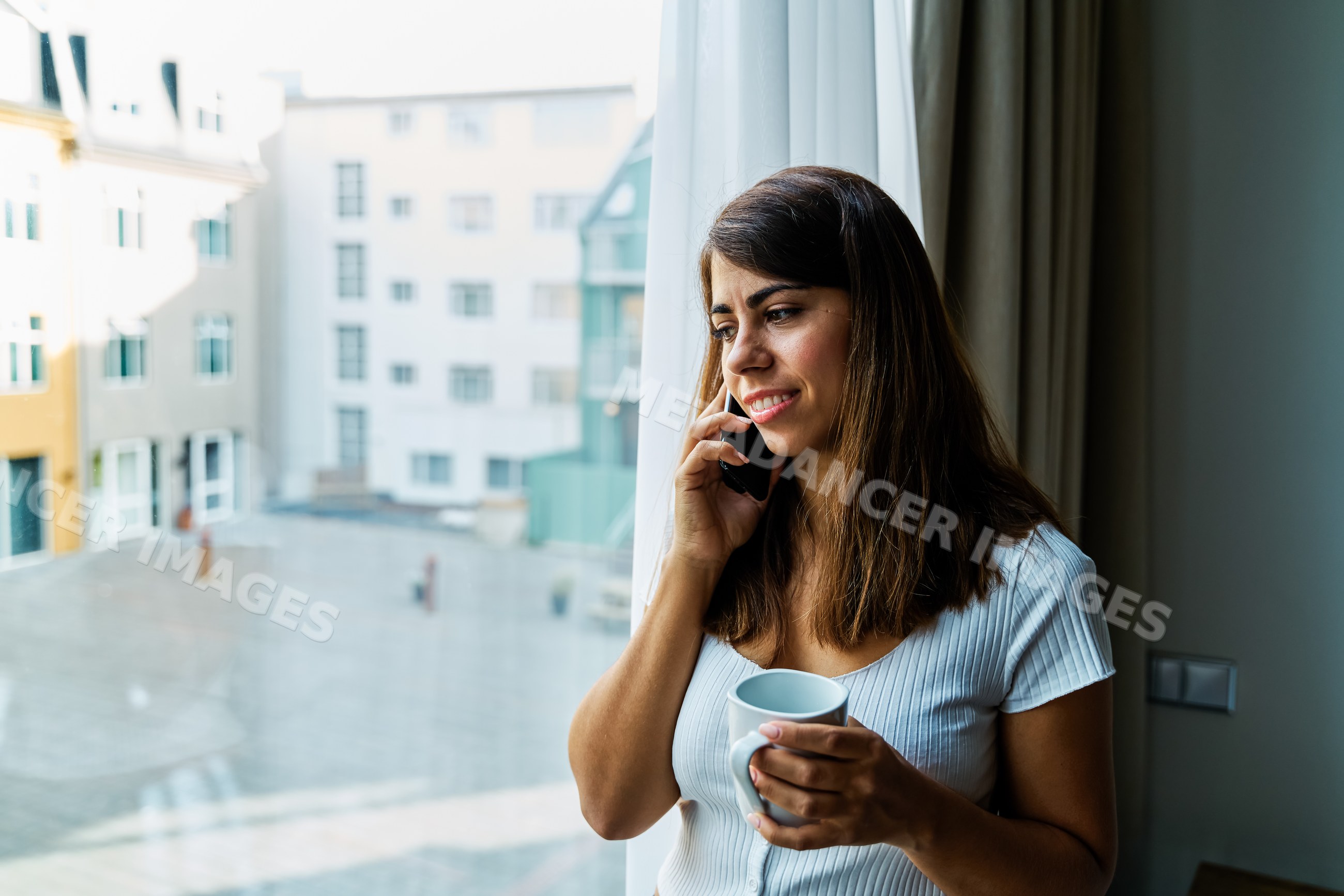 A woman talks on her phone with a mug