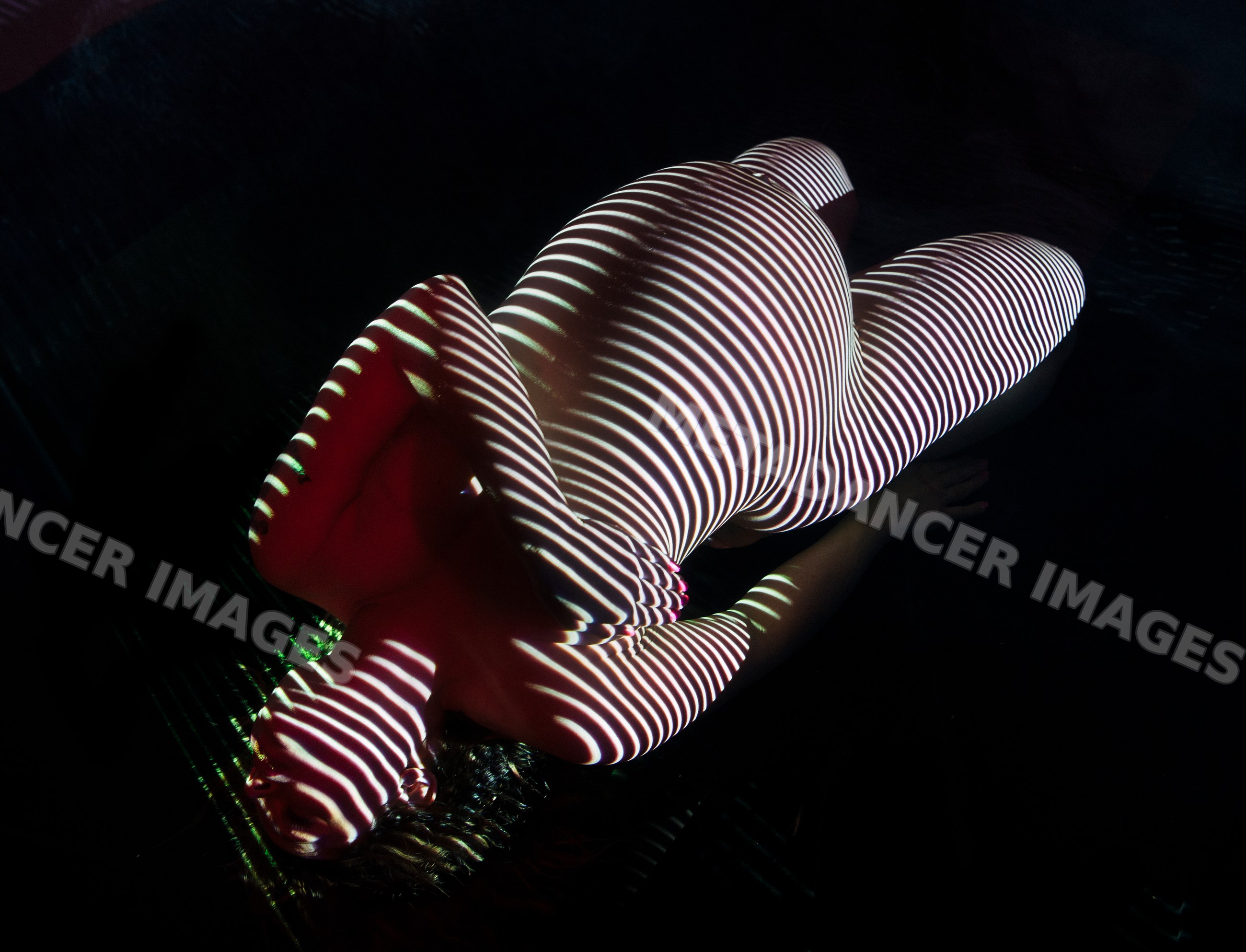 Pregnant white woman with striped light body art lying