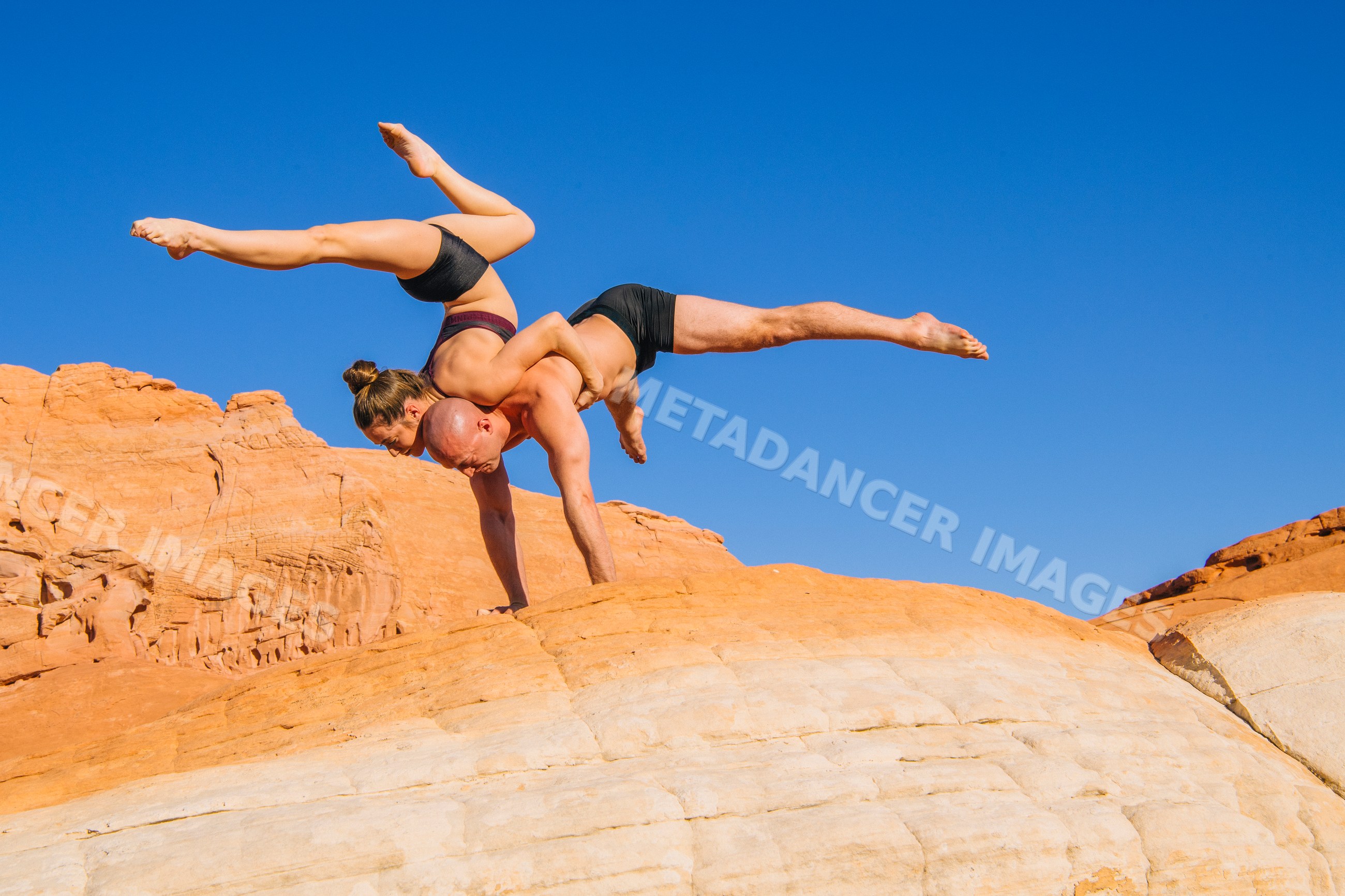 Acrobatic yoga balancing on rocky desert landscape