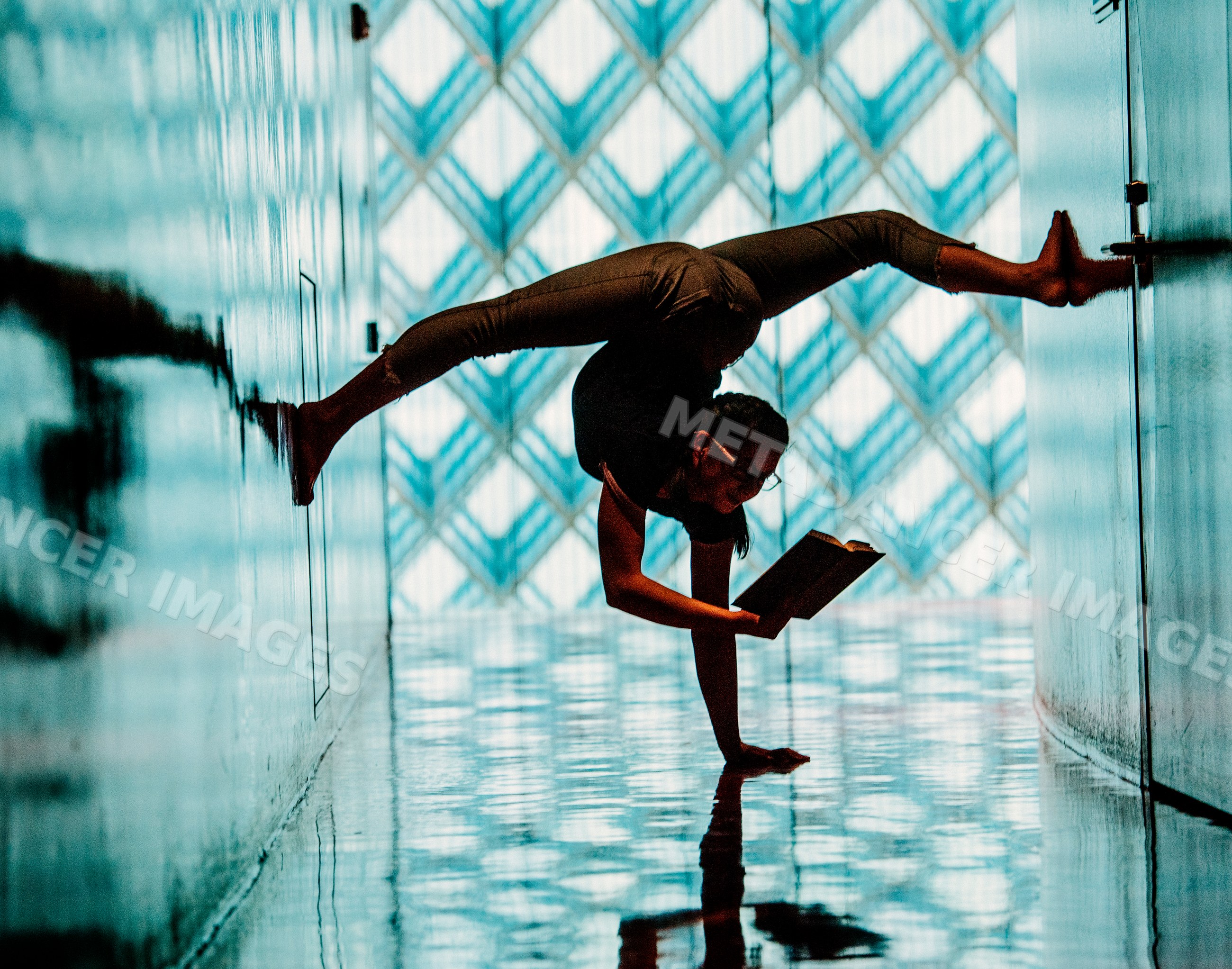 A woman performs a handstand reading a book in a library