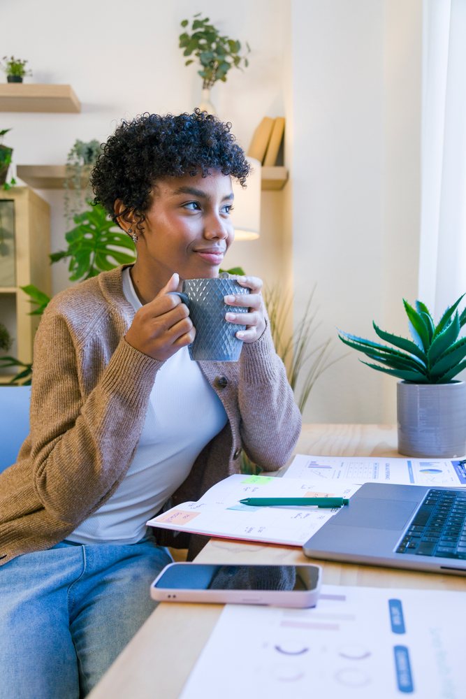 African American woman drinking coffee while working in a home office
