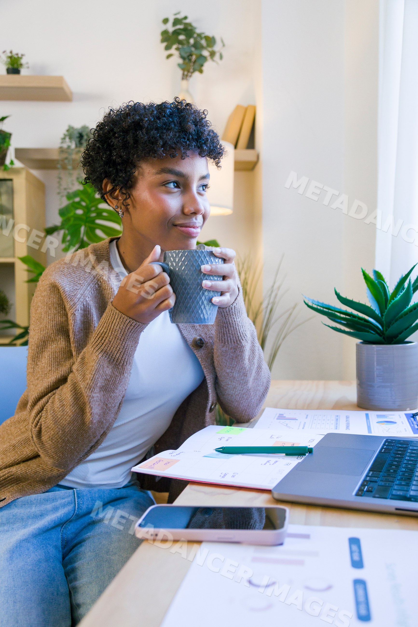 African American woman drinking coffee while working in a home office