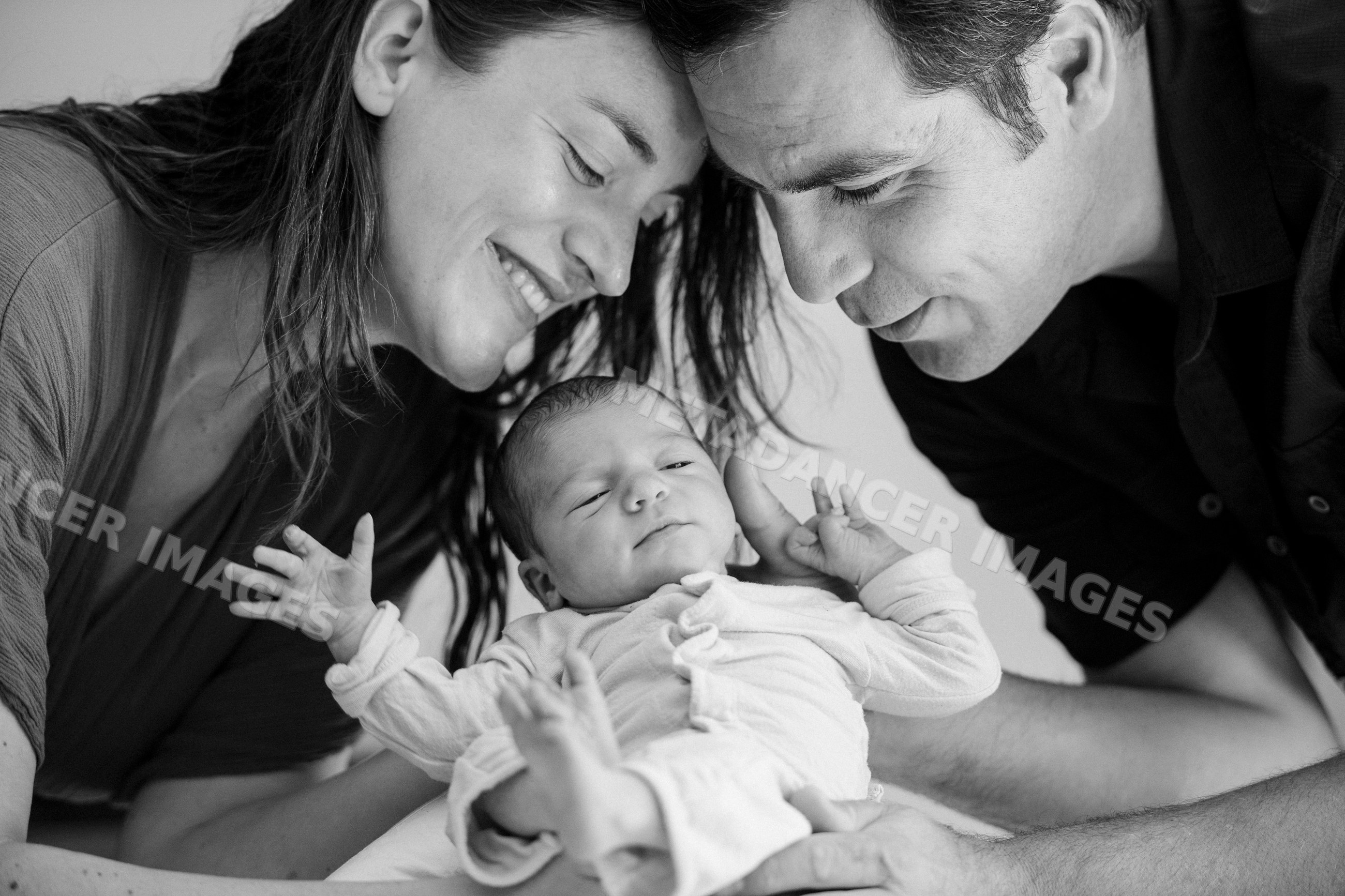 Newborn baby with parents sharing a tender moment