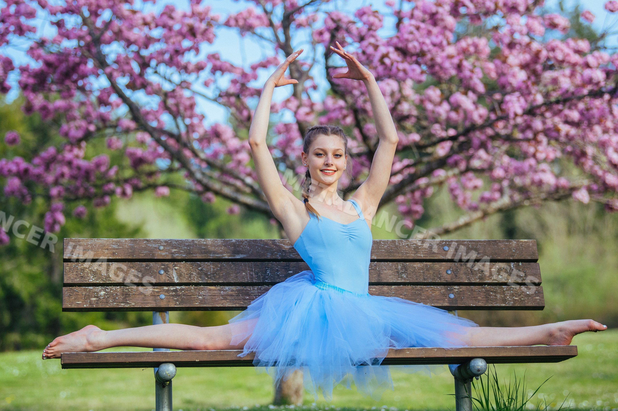 Ballet white dancer performing a split on a bench in a spring park