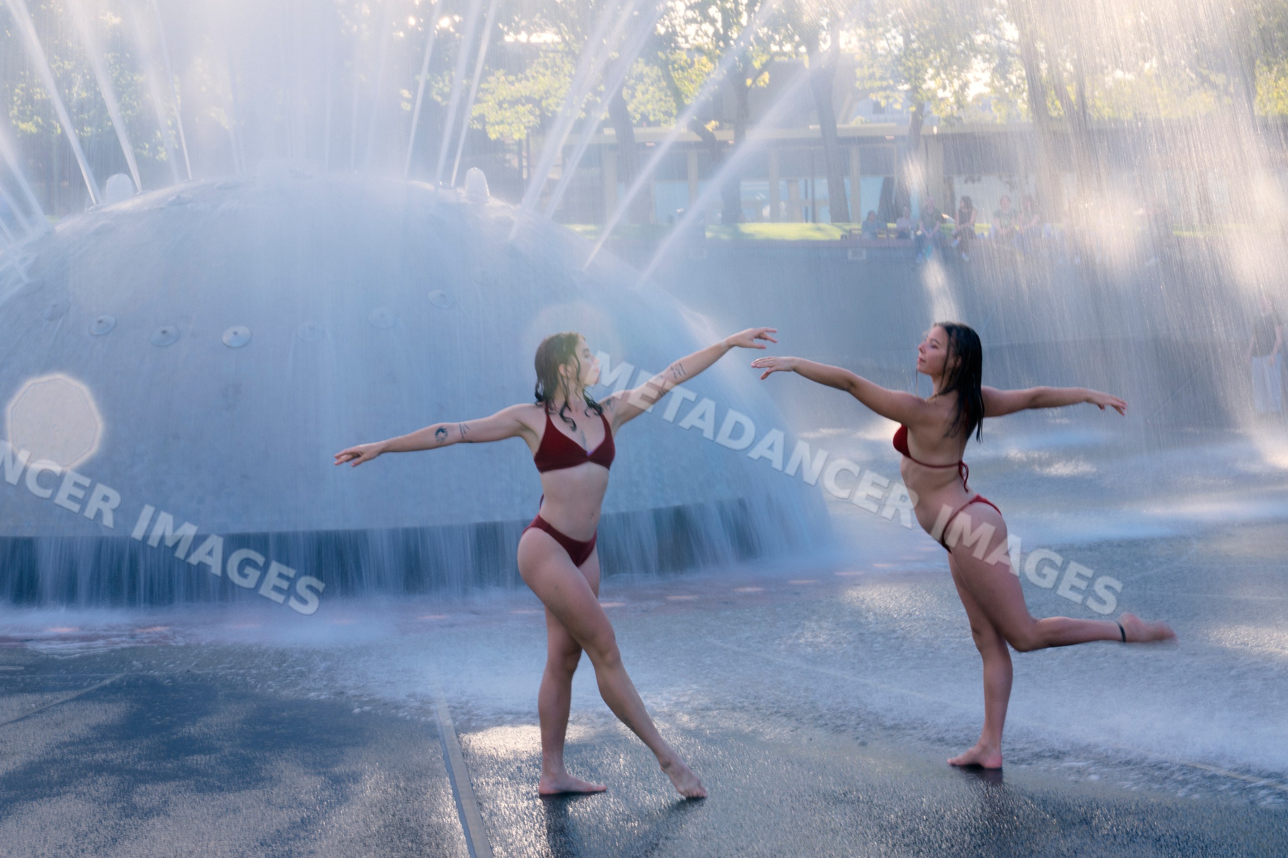 White women dancing gracefully near large water fountain outdoors