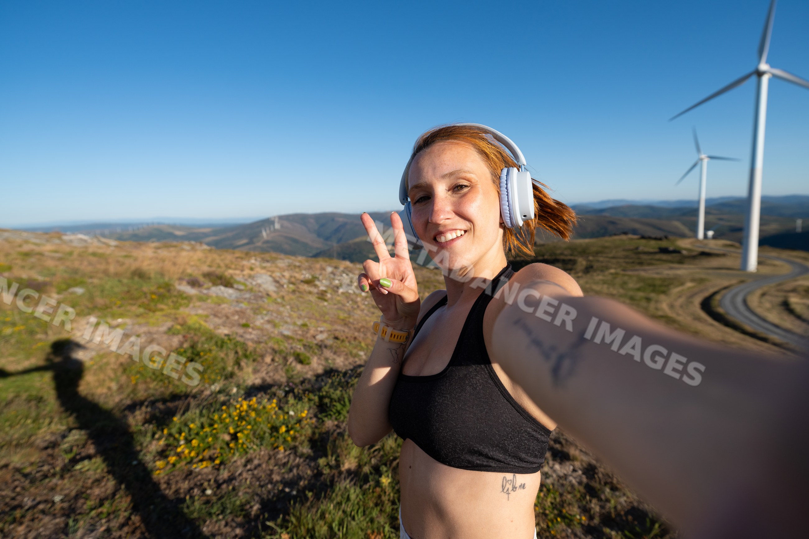 Young white woman takes a selfie at a wind farm in Galicia, Spain
