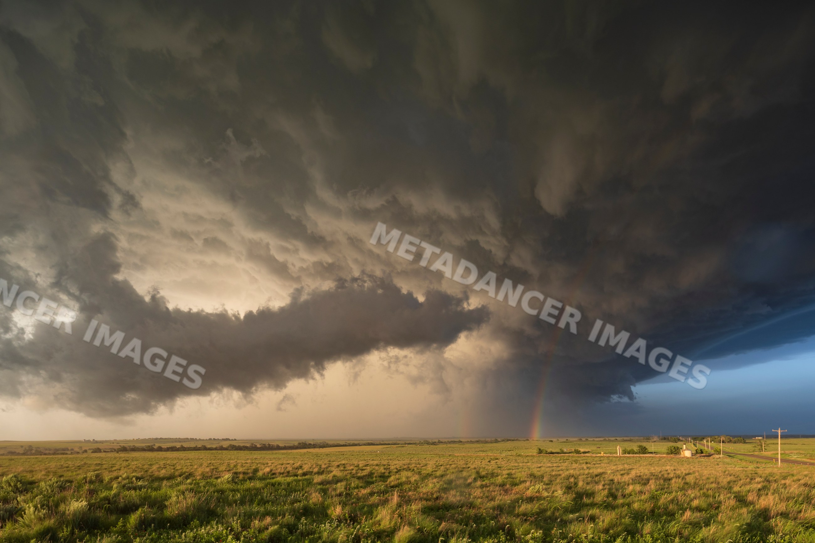Back side of Supercell storm with rainbow over rural field
