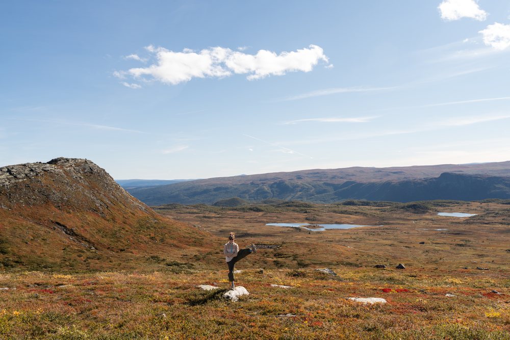 Person stretching in autumn mountain landscape with lakes