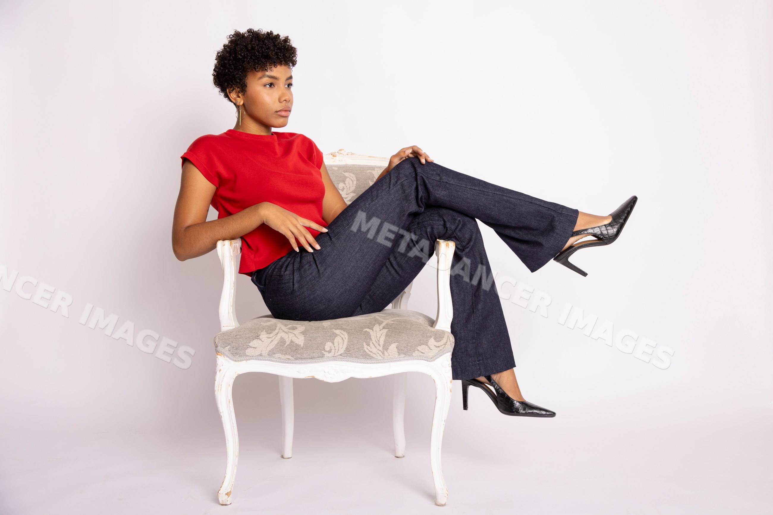 Hispanic woman in red top and black pants sitting on ornate chair
