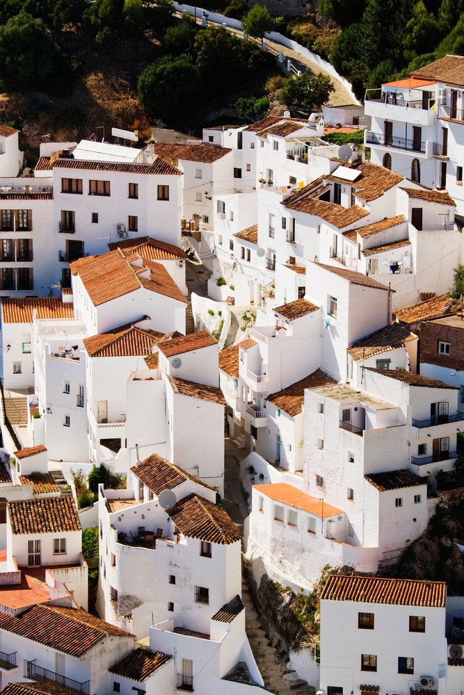 Overview of white buildings clustered on the hillside town of casares