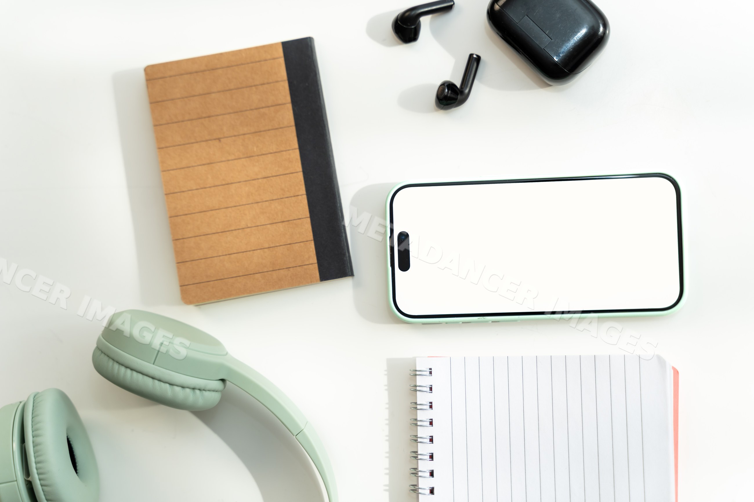 Smartphone with headphones and notebooks on white desk