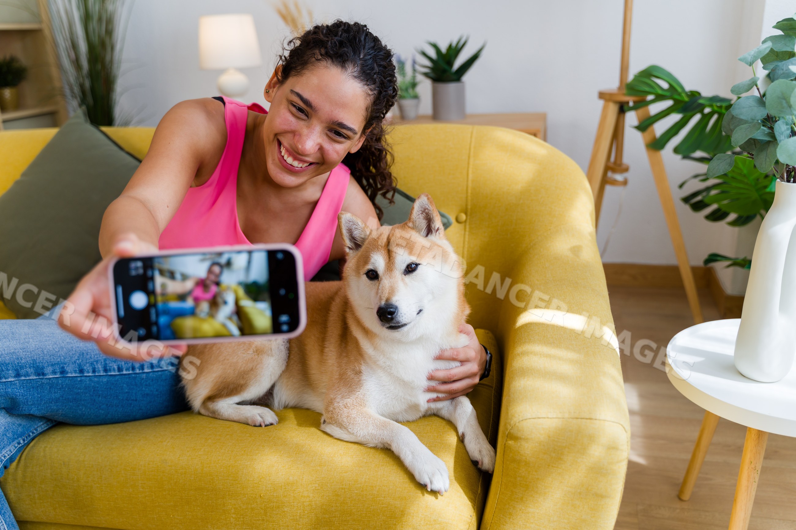 A Hispanic woman happily takes a selfie with her dog