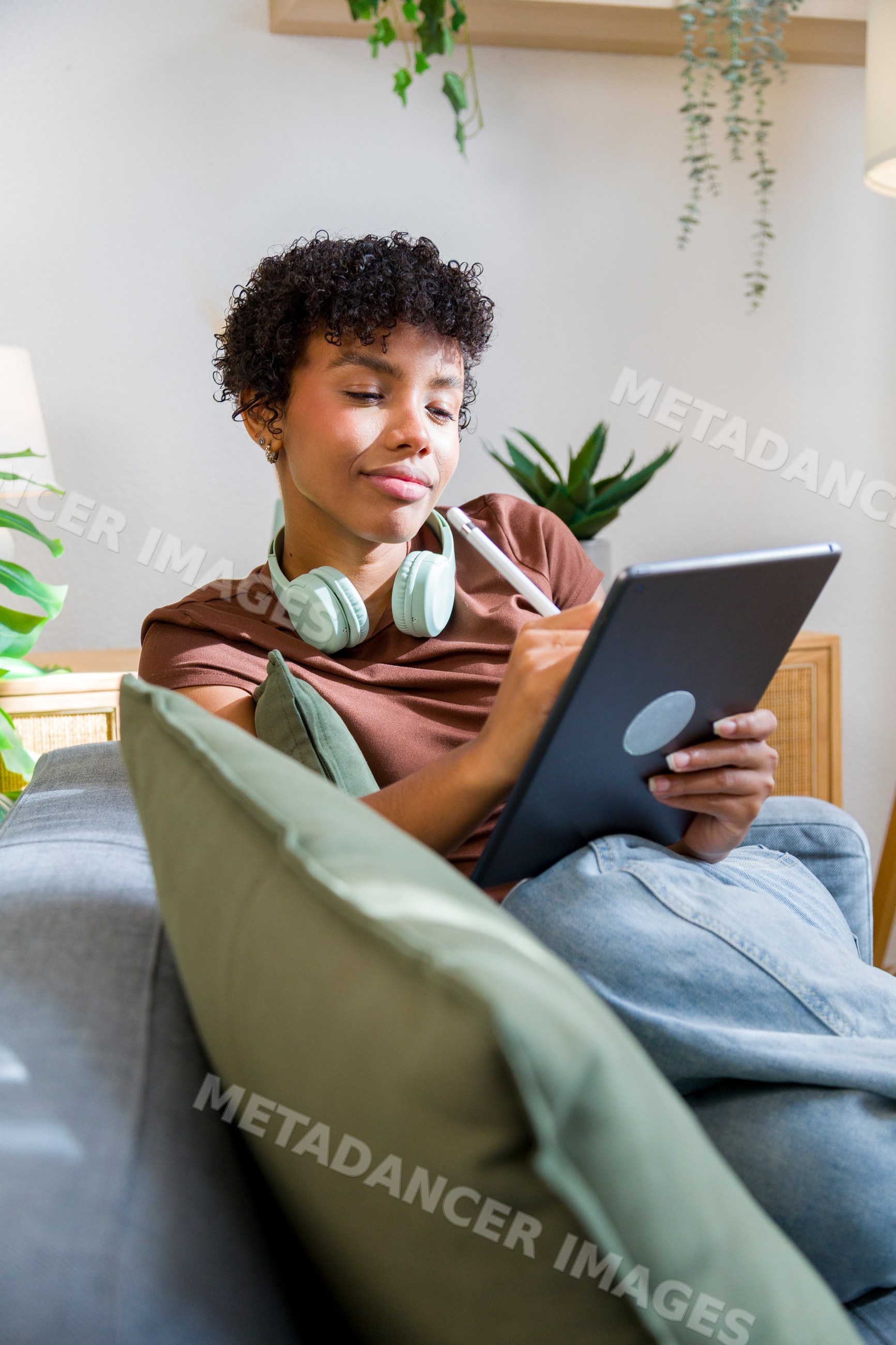 African American woman using tablet and stylus on sofa at home
