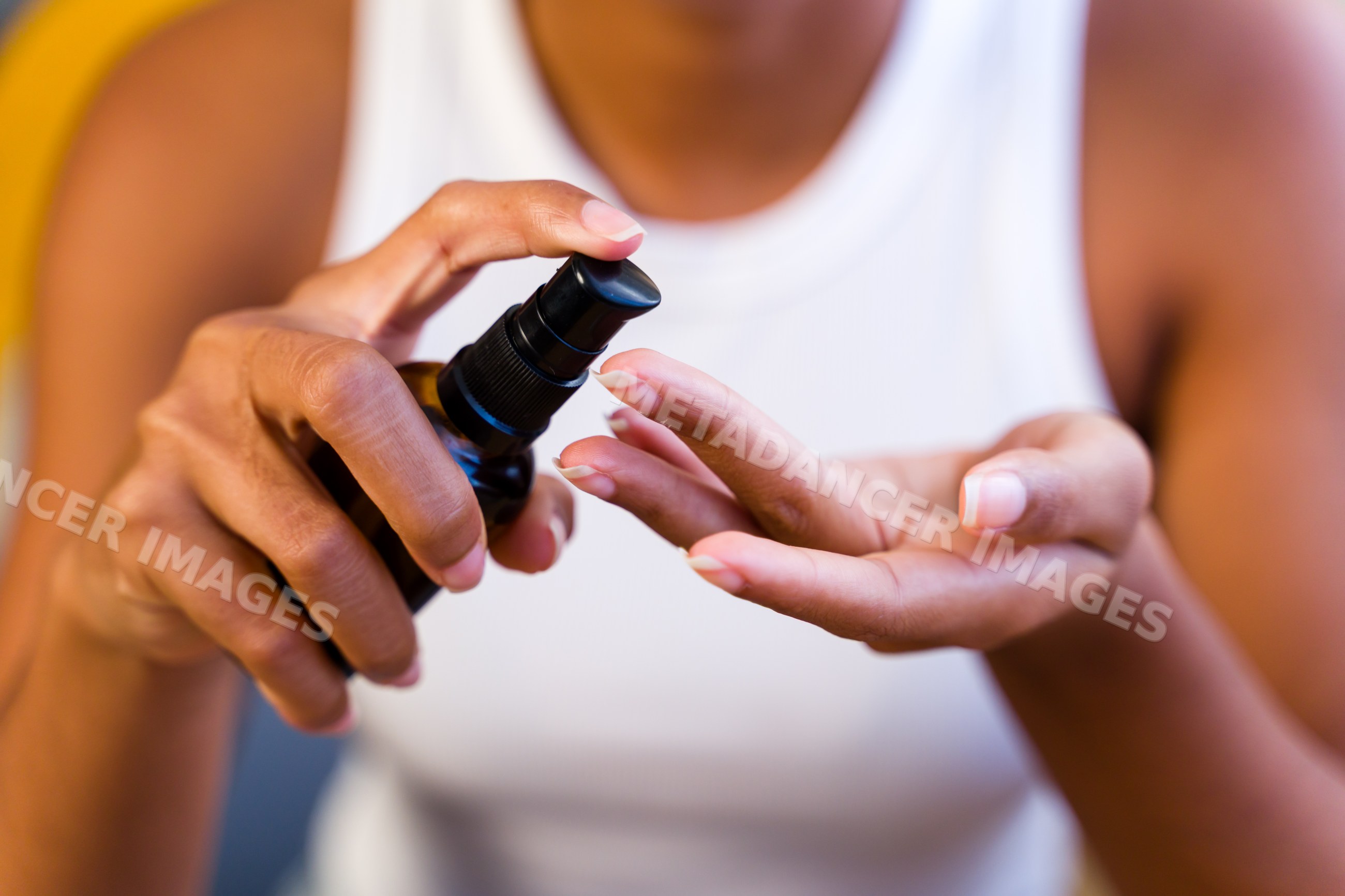 Hands applying lotion from a black pump bottle