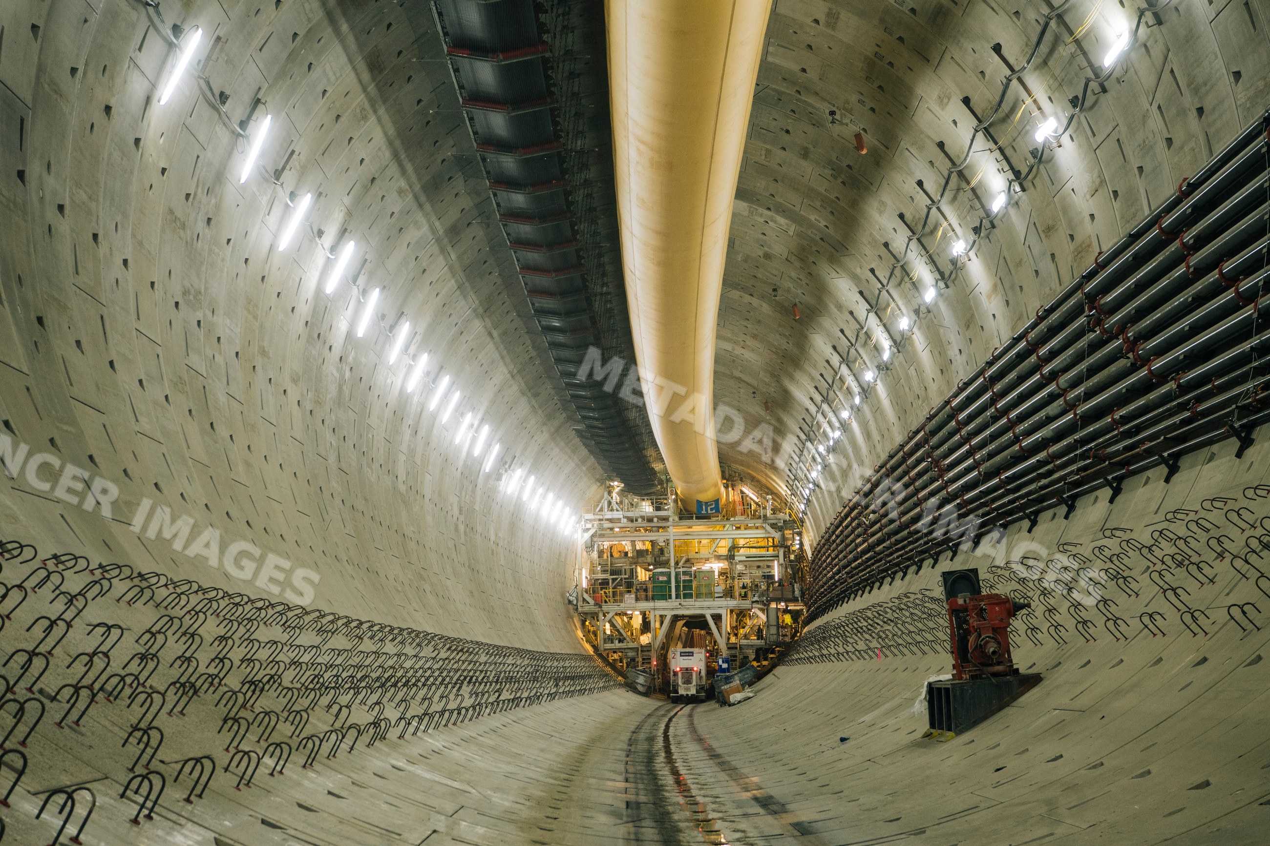 A large concrete tunnel with drilling equipment under construction
