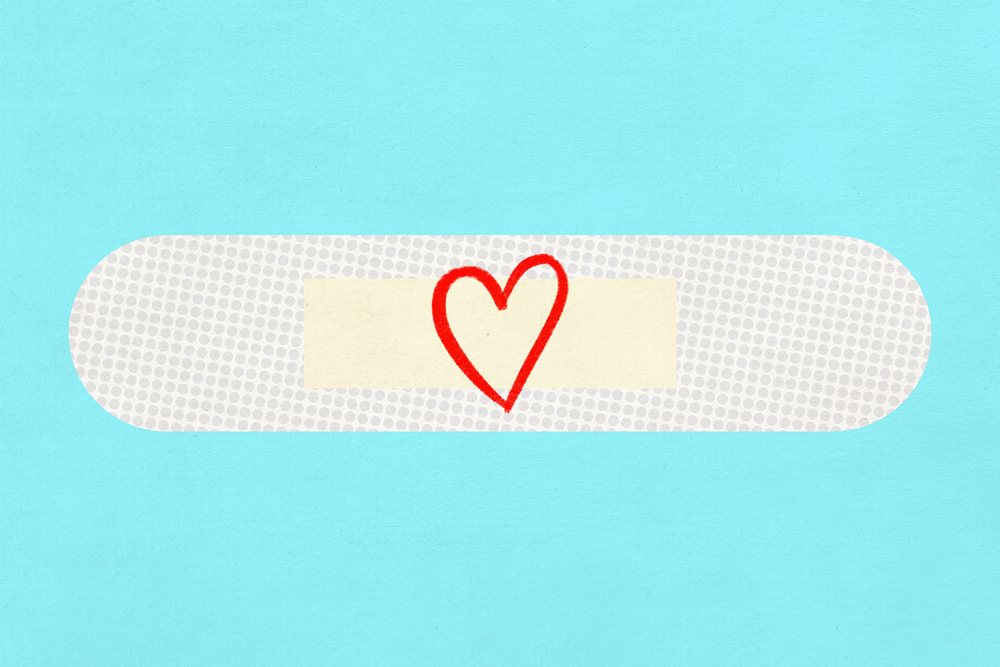 A white adhesive bandage with a red heart drawing on blue background