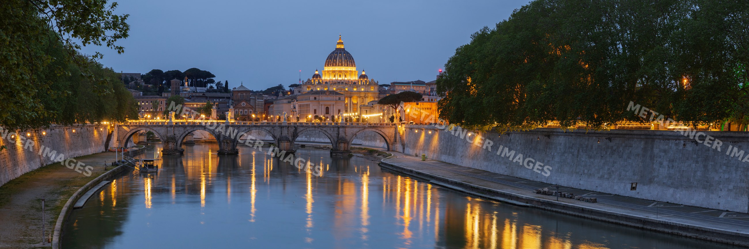 View of the Basilica of St Peter's at dusk across the Tiber River