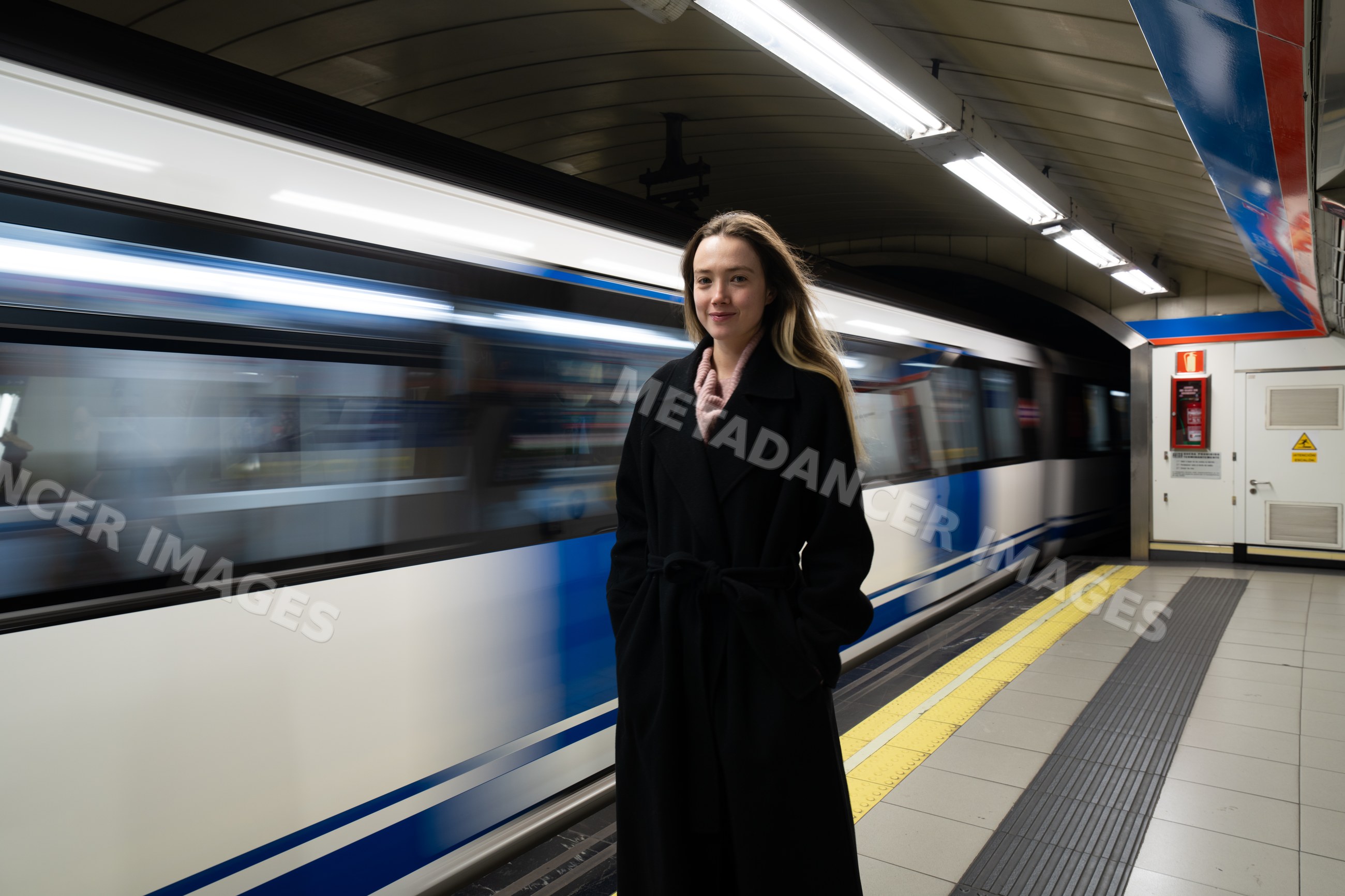 White woman standing on subway platform as train passes