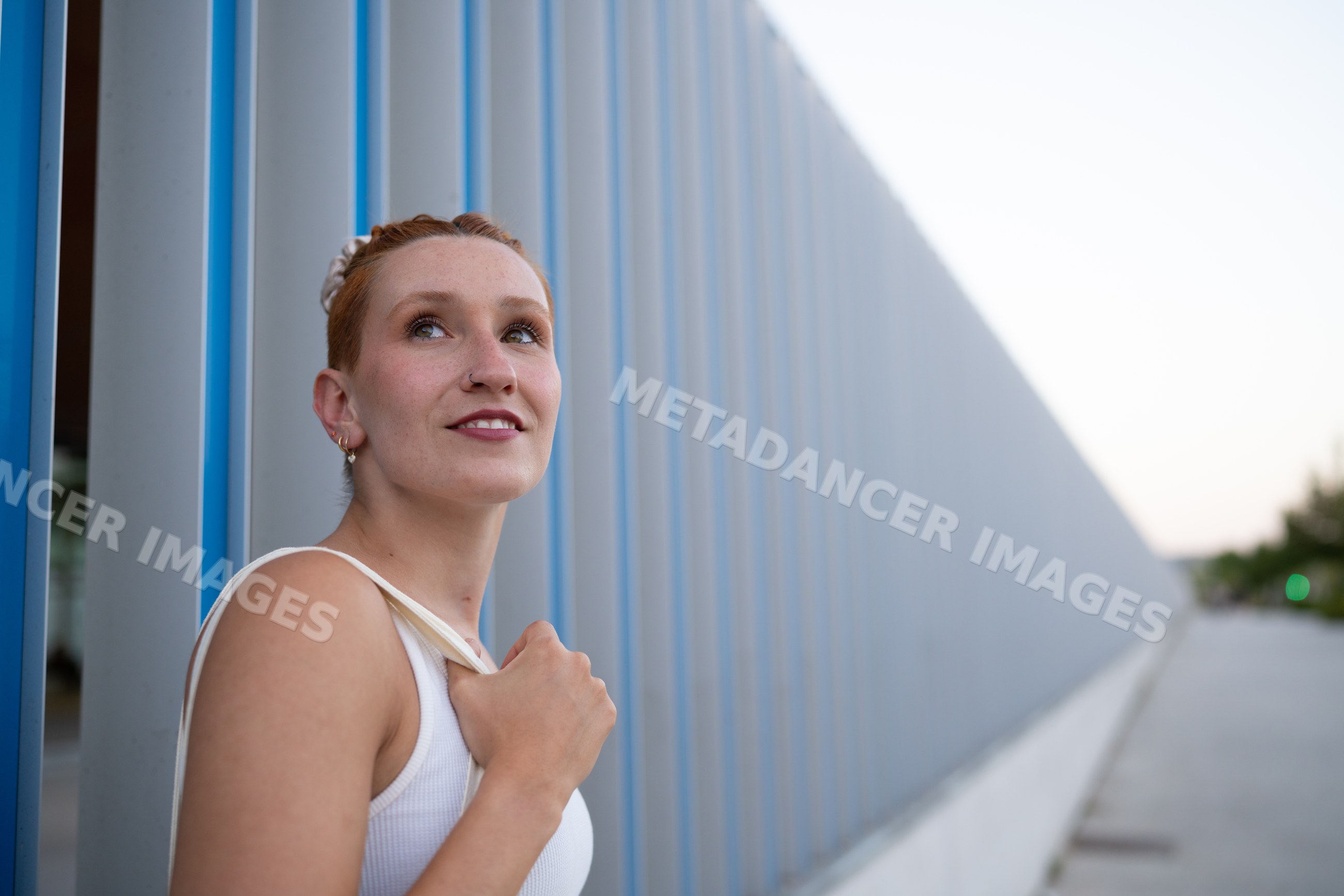 A young white woman looks thoughtfully beside a modern wall