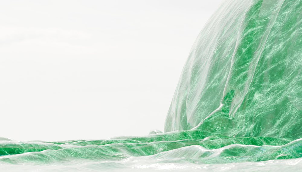 Close-up of a large green ocean wave flowing with white foam