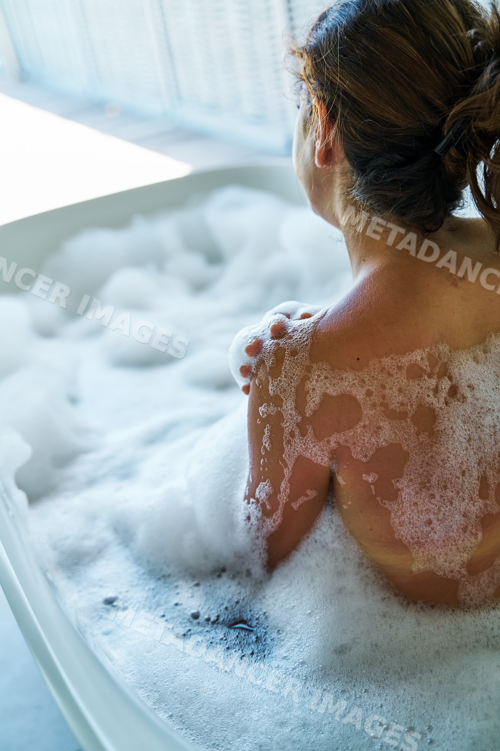 White Woman relaxing in a bubble bath tub filled with foam