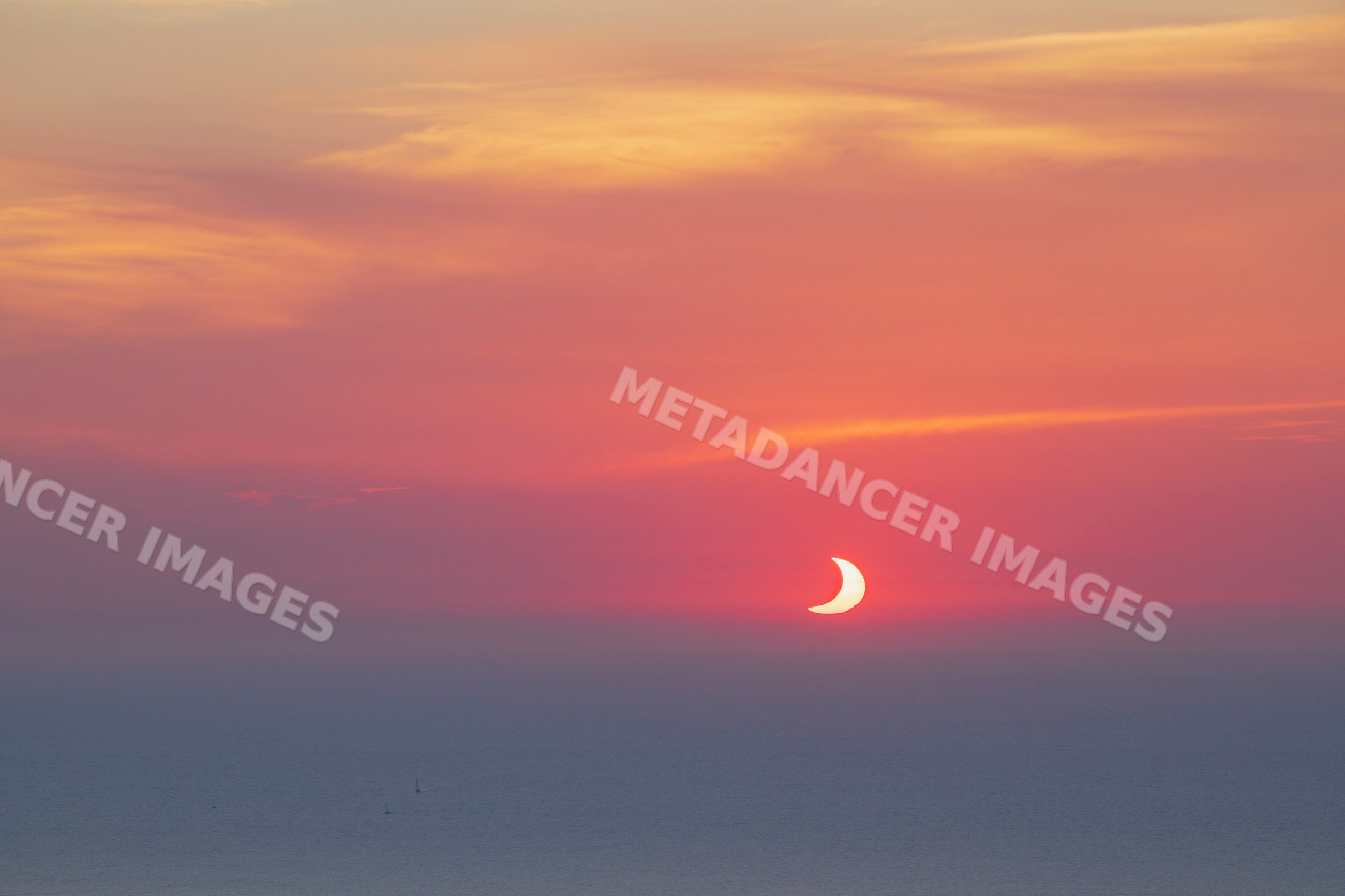 Sun partially eclipsed at sunset over sea near valldemossa Mallorca