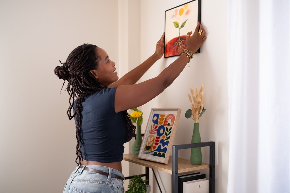 African American woman decorating a home office wall in a office