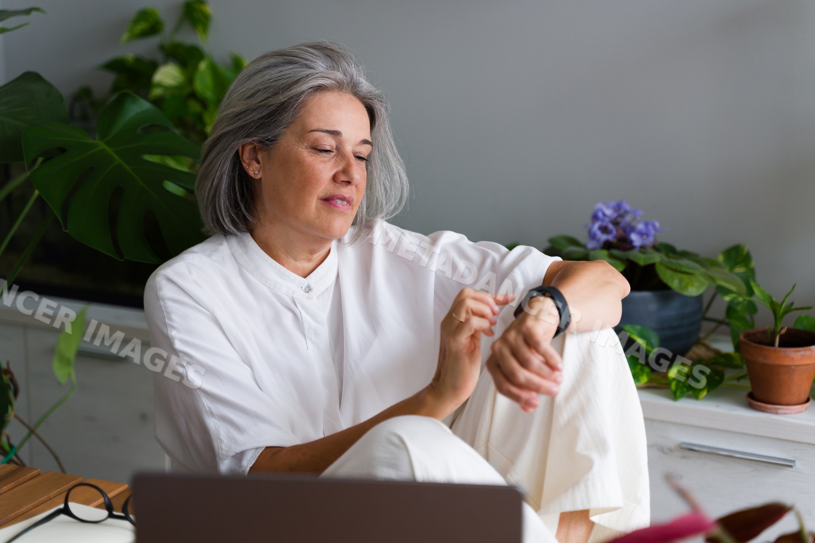 Middle-aged white woman checking wrist device indoors