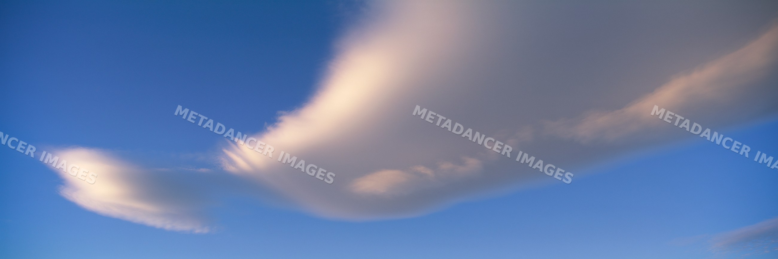 White clouds stretching across a blue sky at sunset