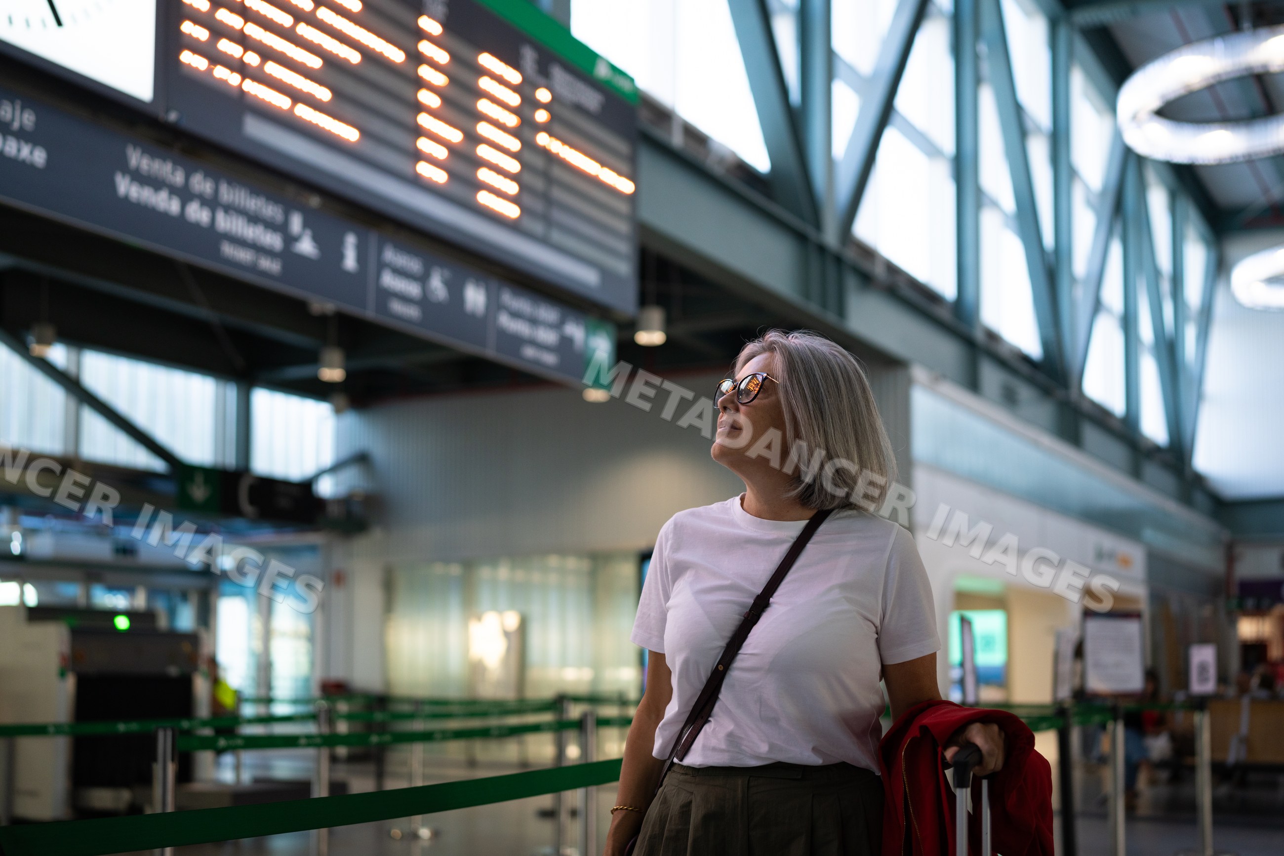 White woman waiting at airport departure ticket counter with luggage