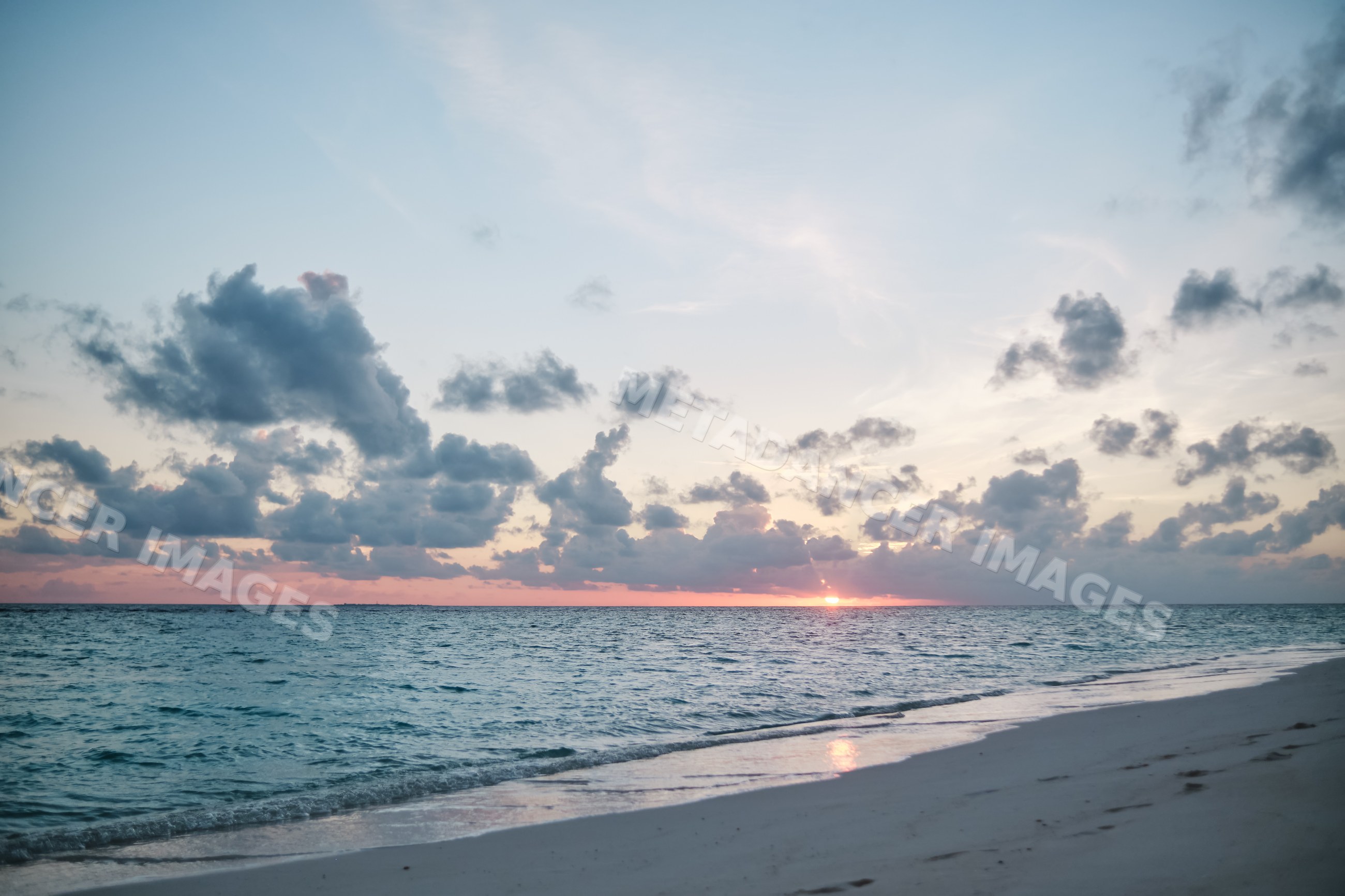 Sunset over the ocean with clouds and a sandy beach in a beach