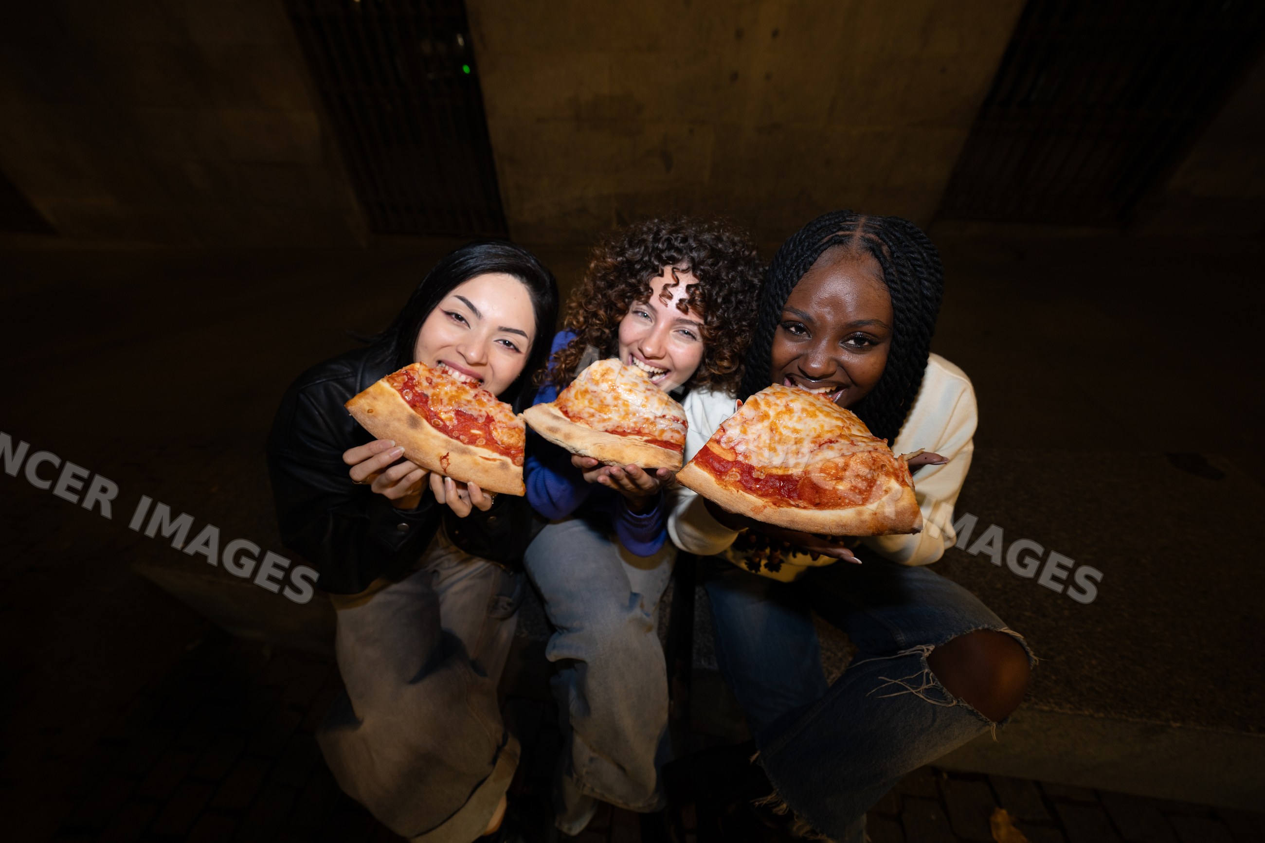 Three Hispanic, white and Black women eating pepperoni and cheese