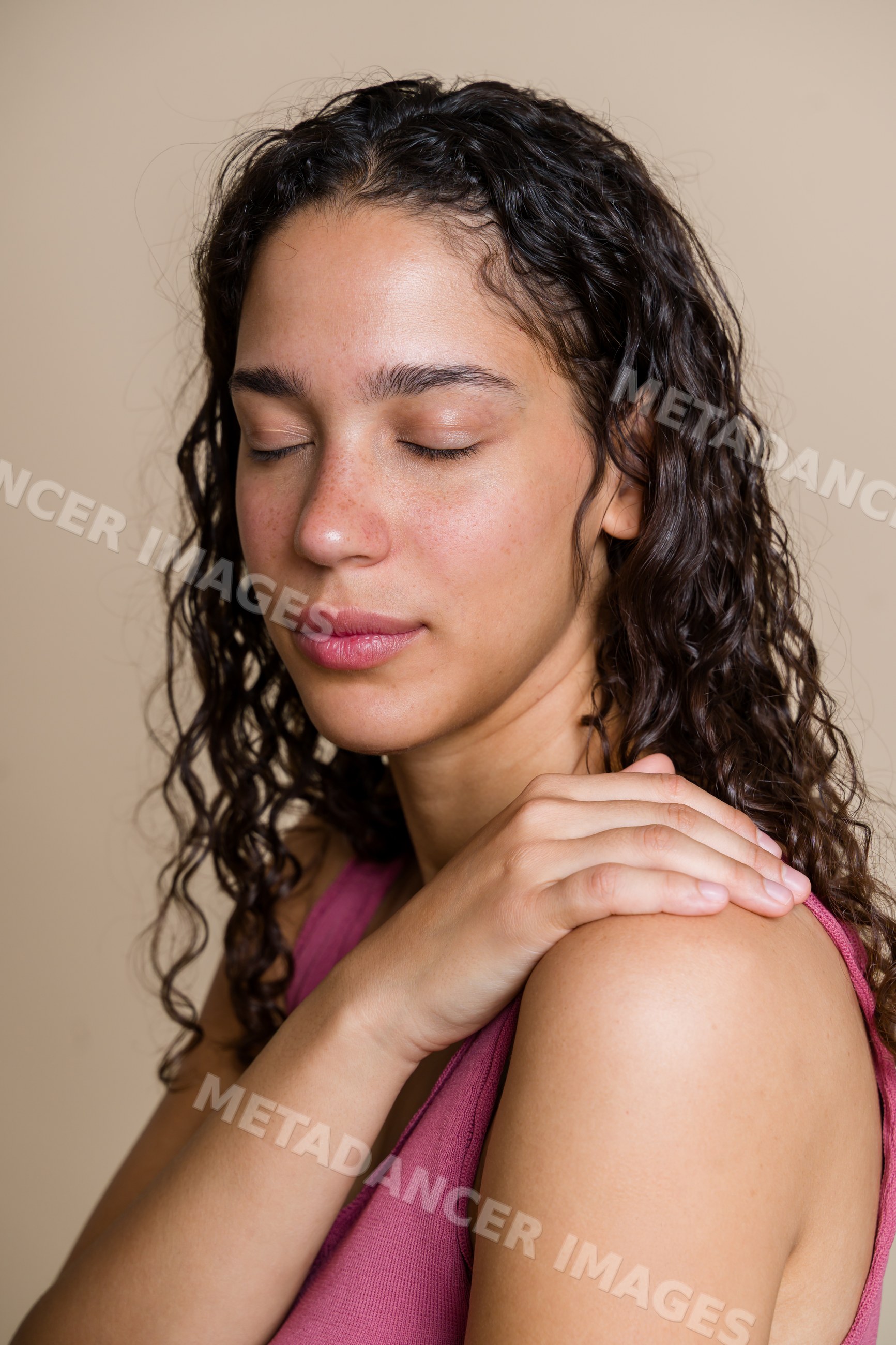 Hispanic woman with curly hair relaxing with hand on shoulder
