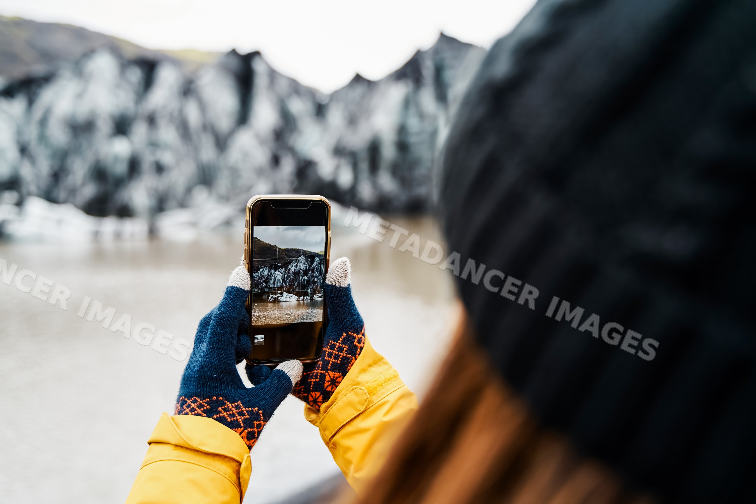A white person captures a photo of an icy glacier landscape