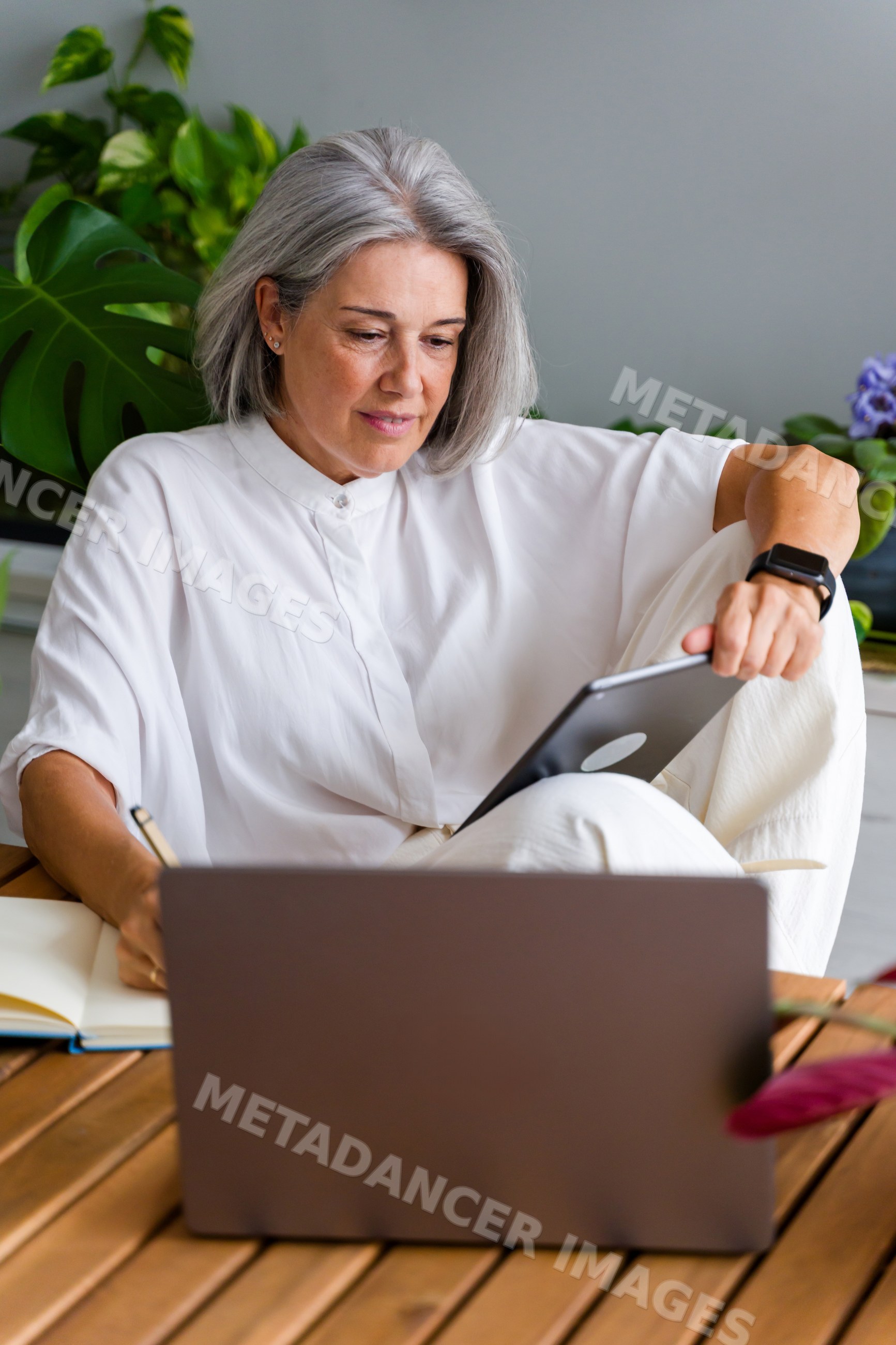 White Woman using tablet and laptop writing